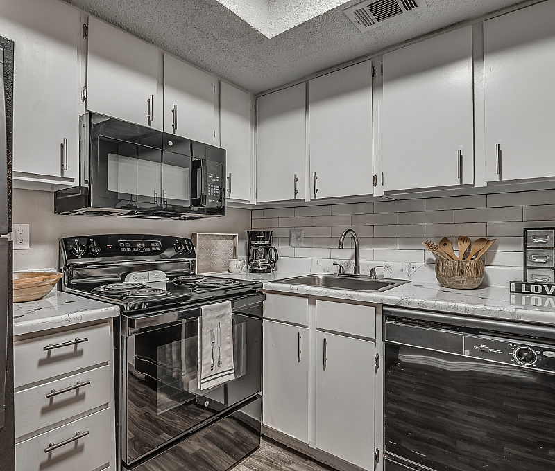 Modern kitchen with sleek black appliances, stylish white cabinetry, and elegant marble countertops.