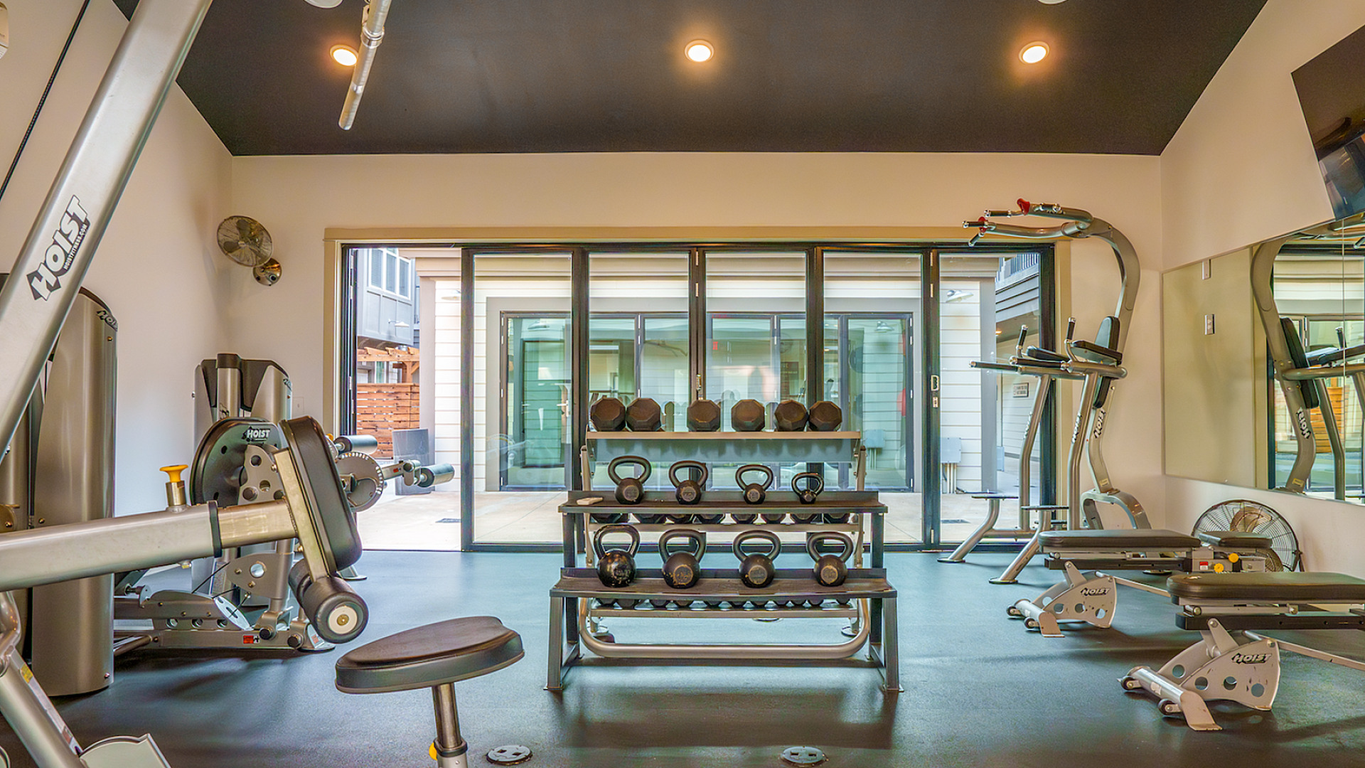 Modern fitness center with state-of-the-art gym equipment, including weights and exercise machines, surrounded by large windows for natural light.
