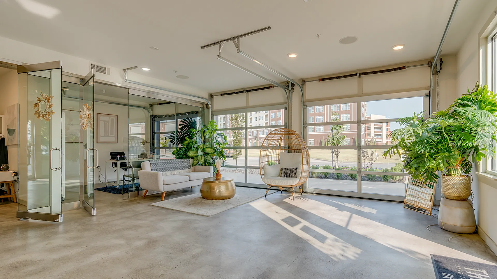 Bright and airy living space with modern decor, featuring glass doors, lush indoor plants, and comfortable seating.