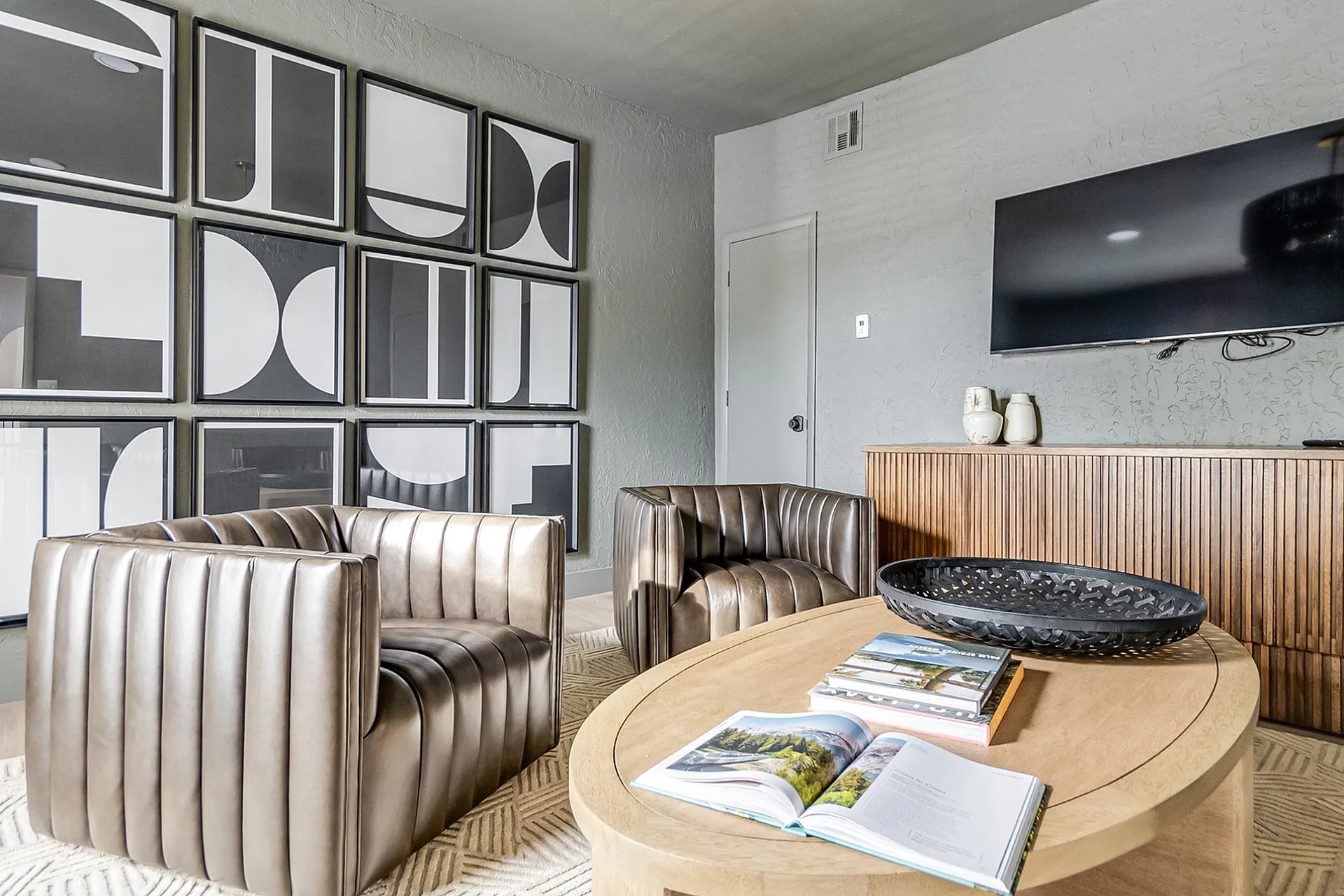 Sophisticated living room with modern art wall, elegant leather chairs, and sleek entertainment setup.