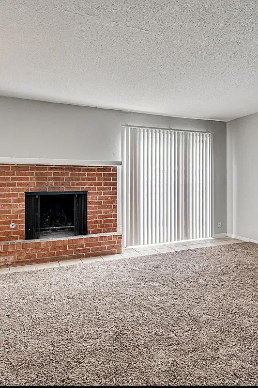 Inviting living room with a cozy brick fireplace and abundant natural light through sliding glass doors.