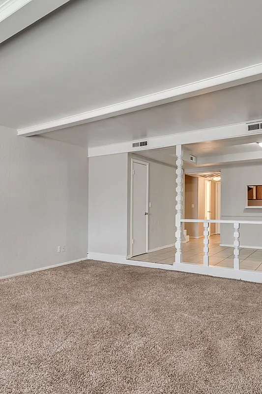 Bright and spacious living area with plush carpeting and stylish architectural detailing. Perfect for modern living.