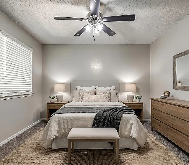 Bright and cozy bedroom featuring modern lighting, a comfortable bed with plush pillows, and elegant wooden furniture.