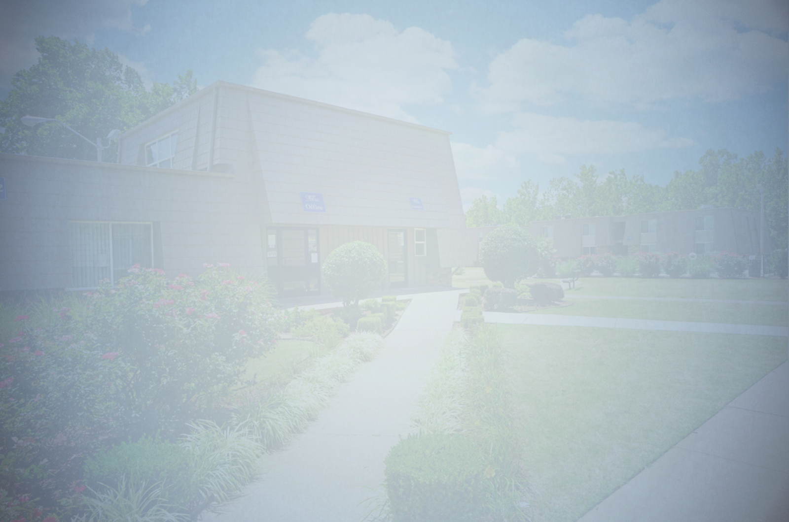 Beautiful apartment complex with lush landscaping, manicured gardens, and modern architecture under a bright blue sky.
