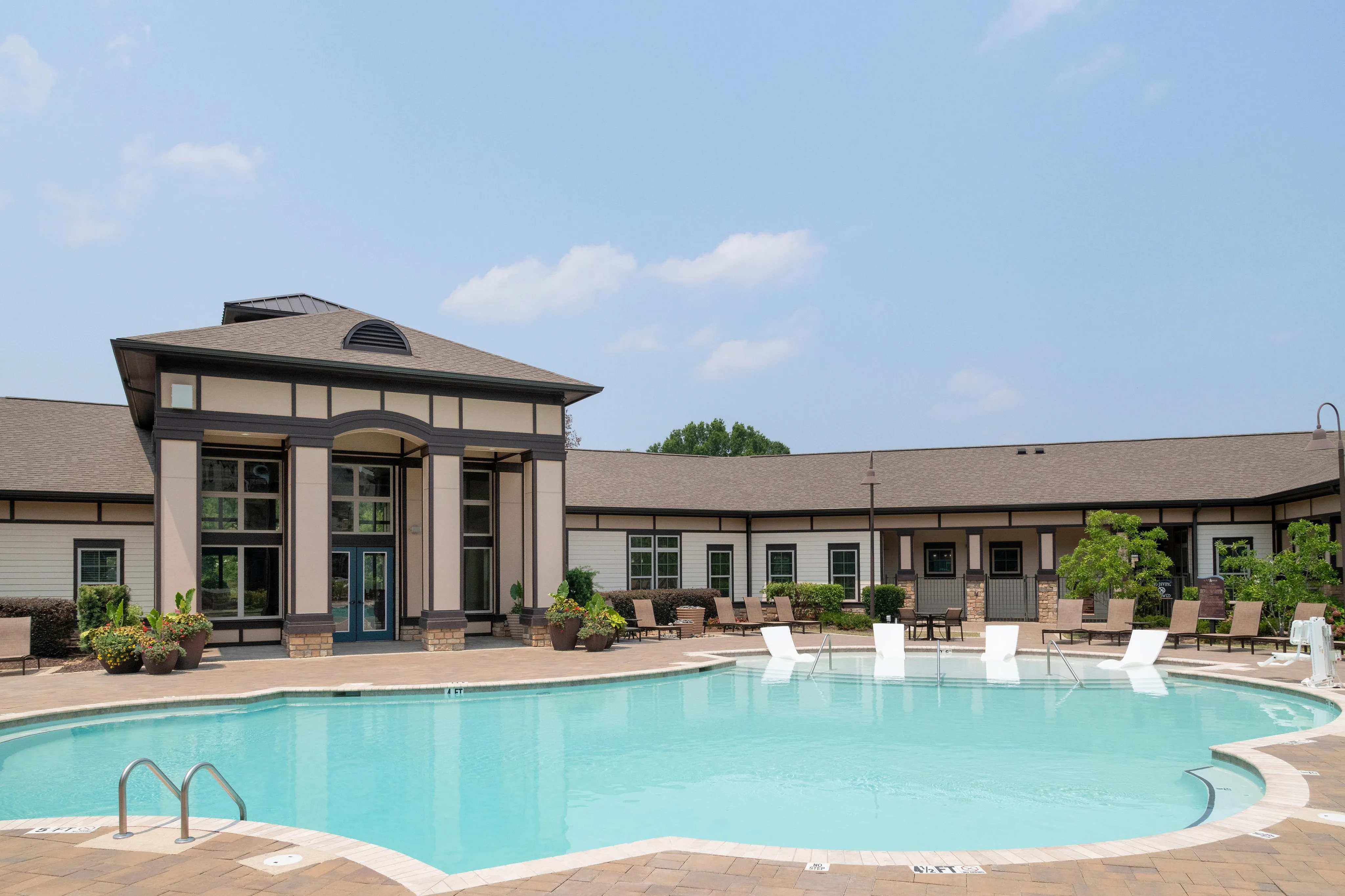 Elegant residential building with a spacious, inviting swimming pool area surrounded by lush greenery.