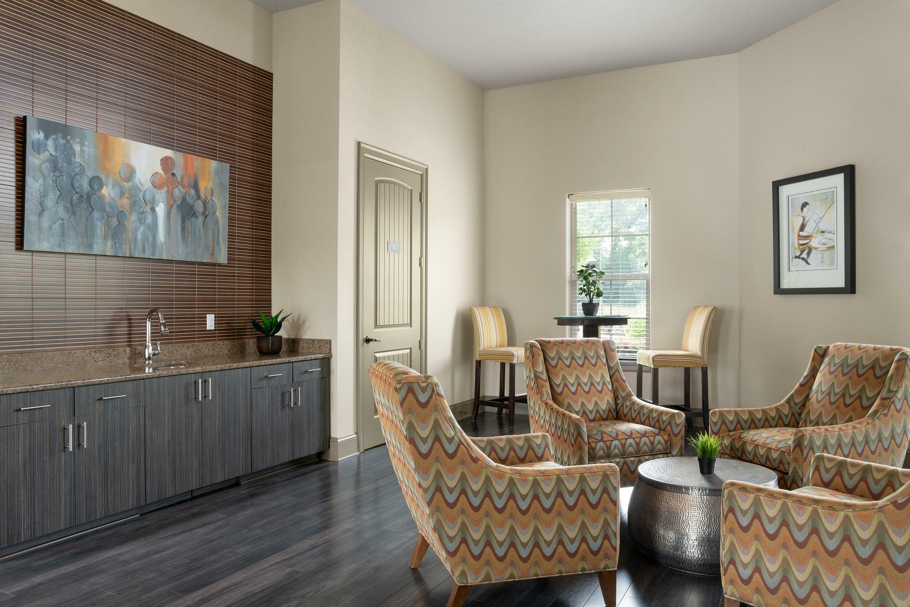 Chic living room with four stylish patterned chairs, a modern art piece, and elegant wooden cabinetry.