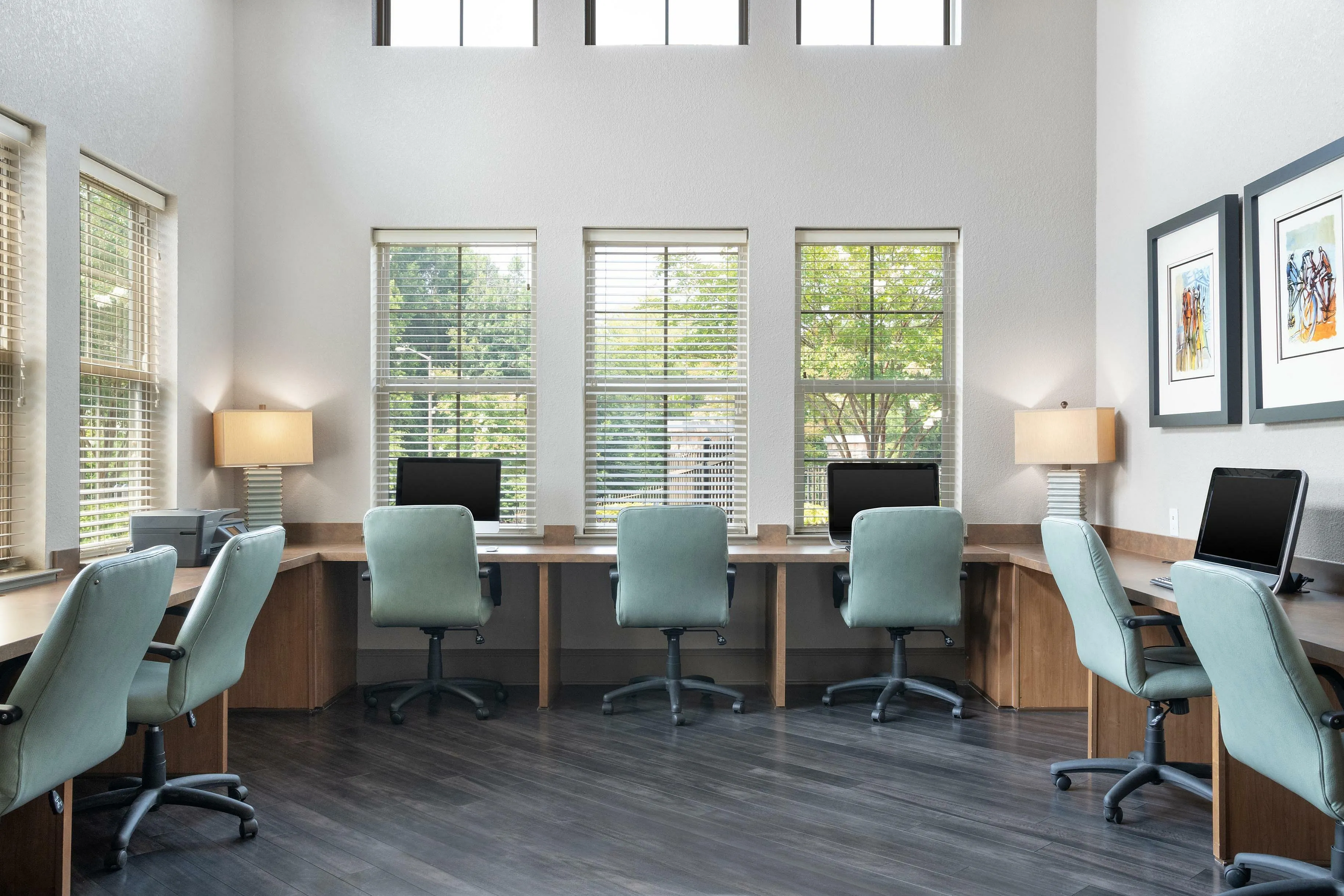 Bright and spacious office space with multiple workstations, large windows, and modern chairs.