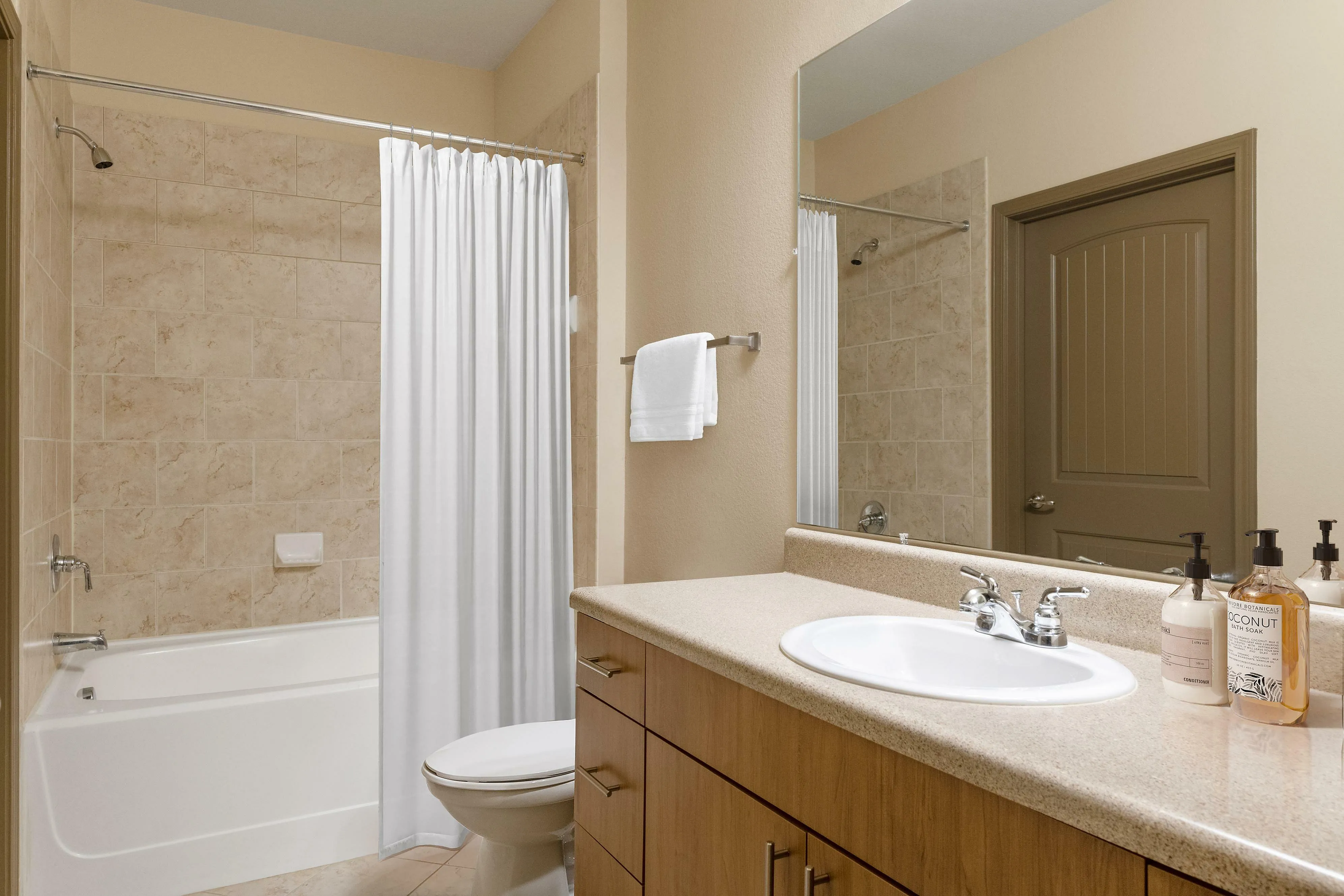 Bright and modern bathroom featuring a bathtub, sleek countertop, and ample storage space.