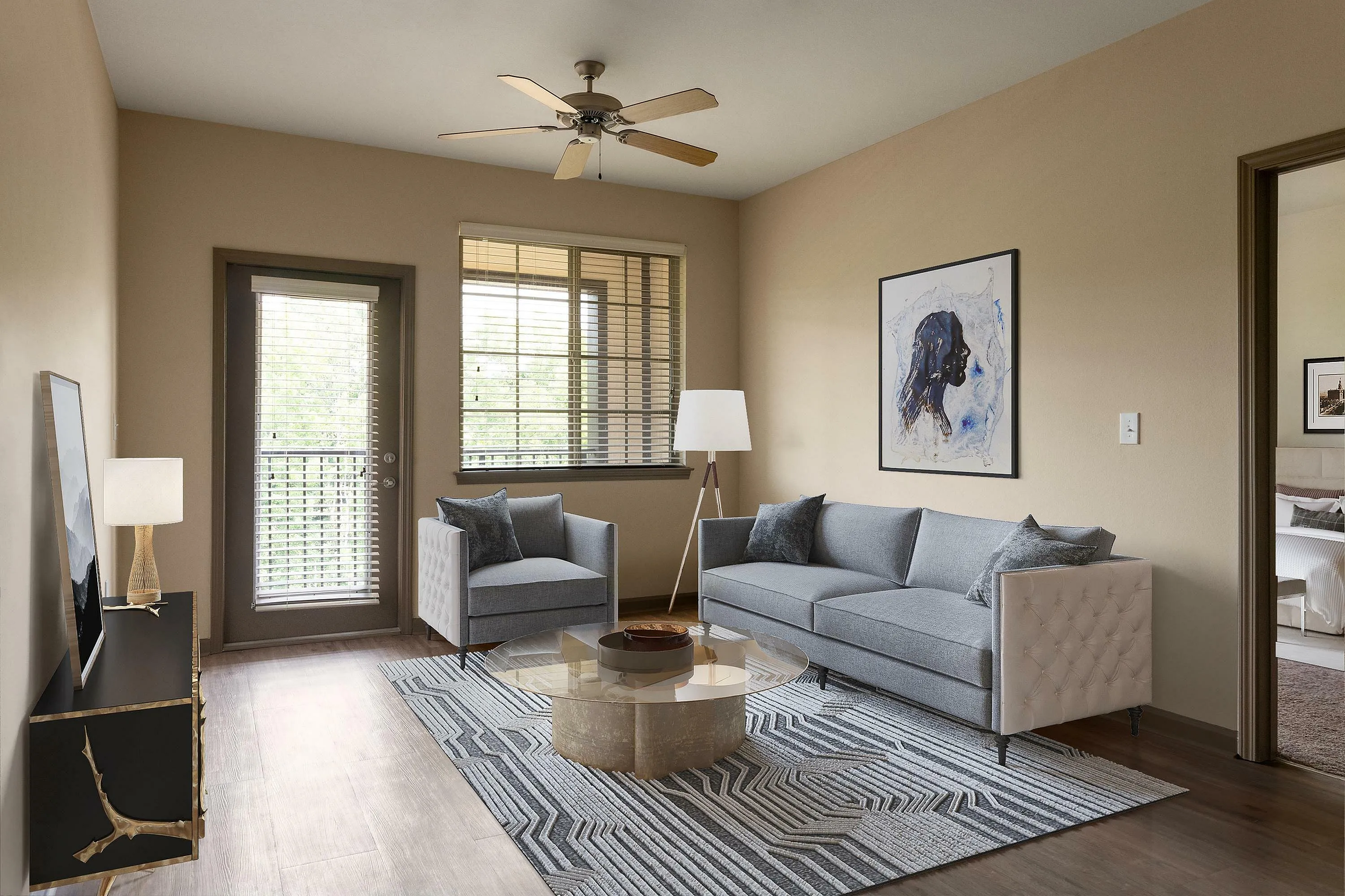 Chic living room with modern gray sofa, stylish armchair, abstract art, and large windows.