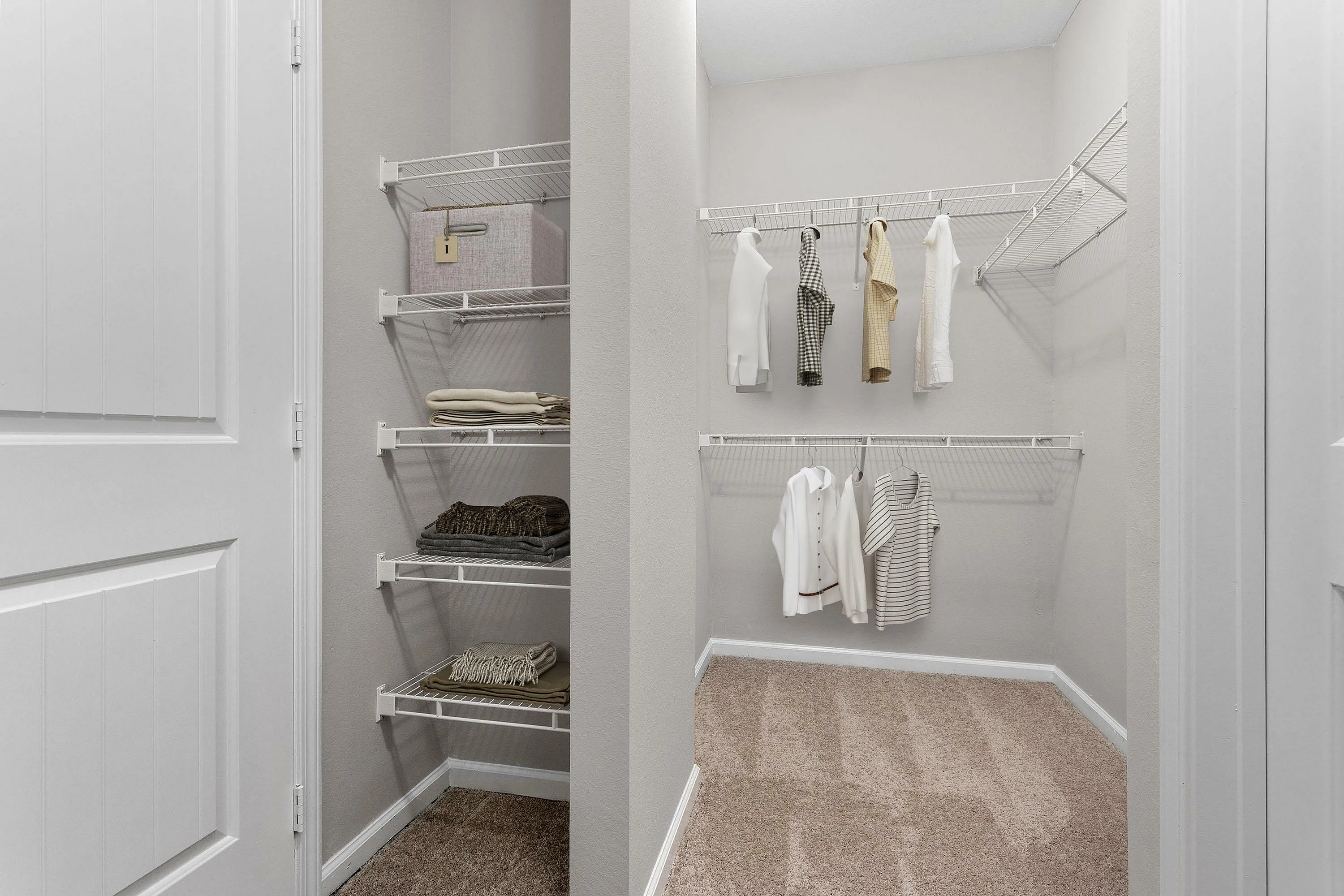 Organized walk-in closet with hanging clothes and shelved accessories.