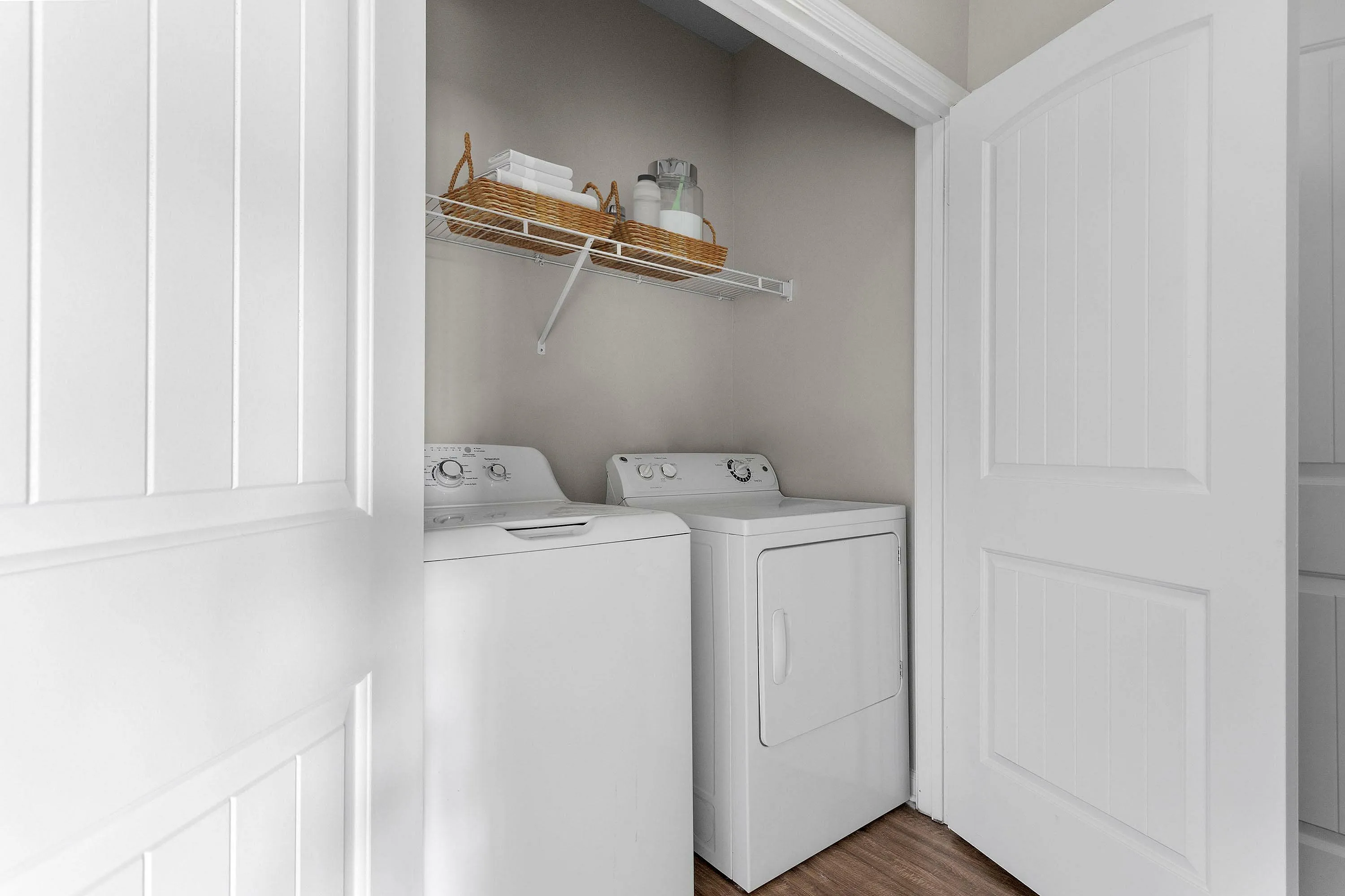 Compact laundry area with washer, dryer, and organized shelving for essentials.