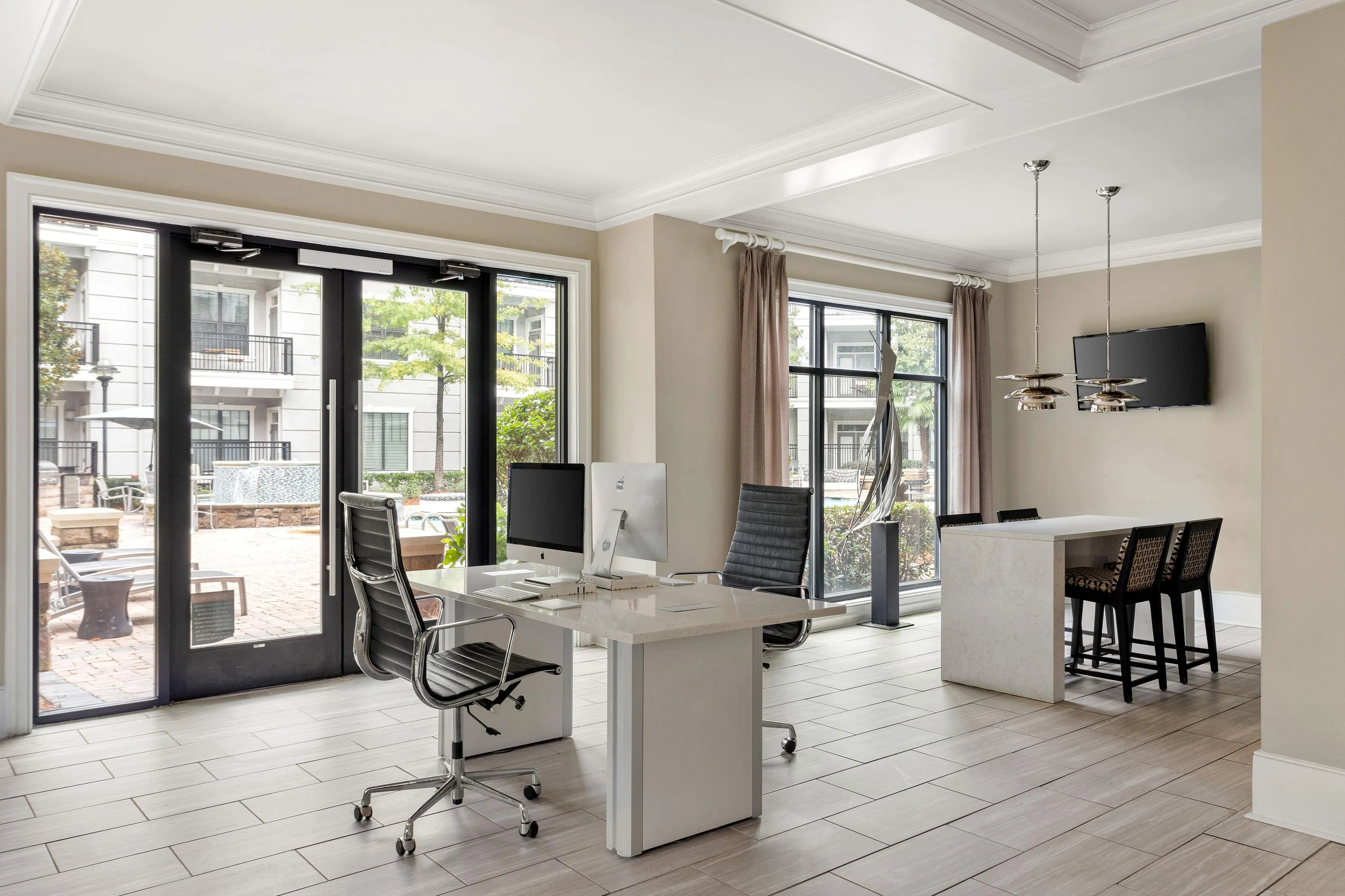 Bright home office with sleek desk, chairs, and large windows overlooking a serene courtyard.