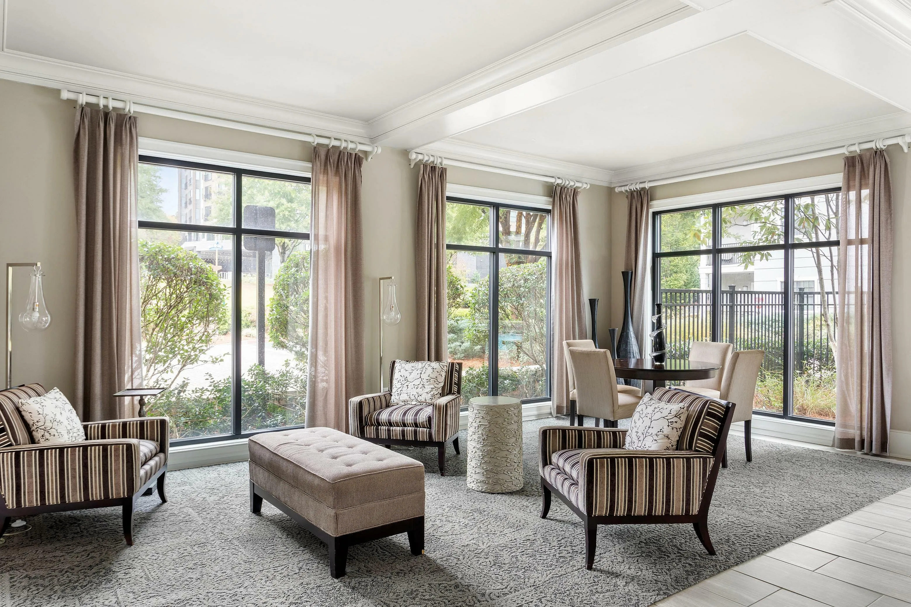 Stylishly furnished living room with large windows, elegant armchairs, and a modern dining area.