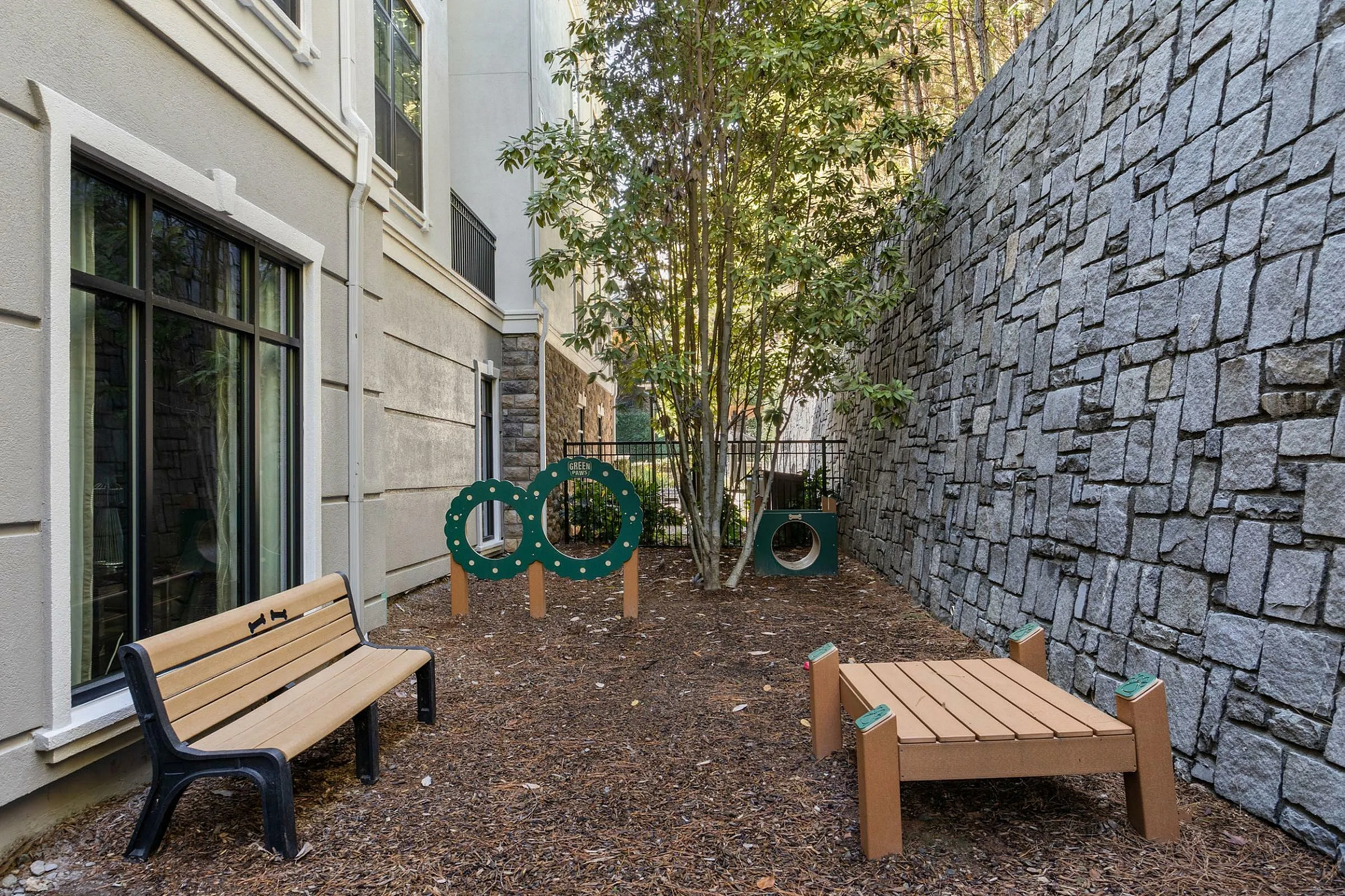 Cozy outdoor community space featuring a bench, play equipment, and lush greenery.