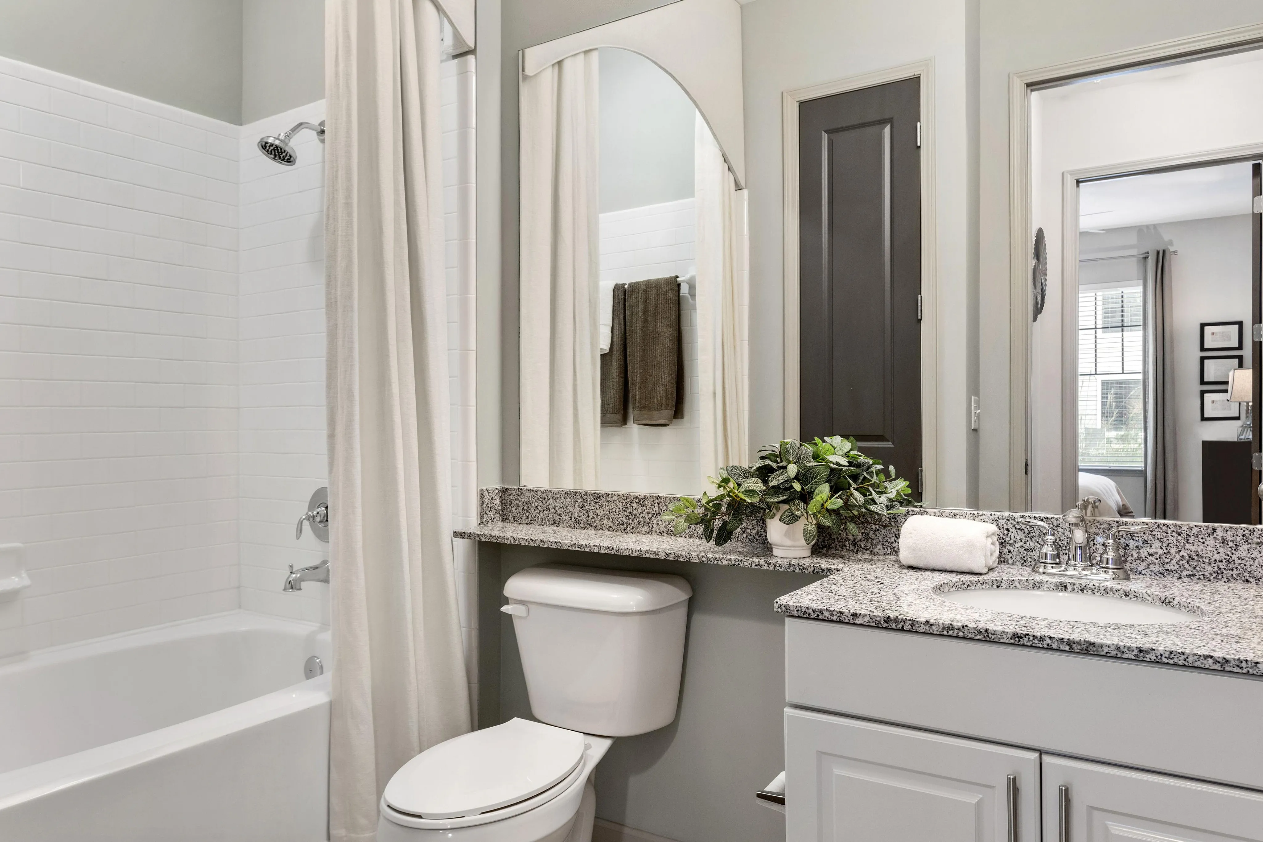 Bright, modern bathroom with a bathtub, sleek granite countertop, and stylish fixtures.