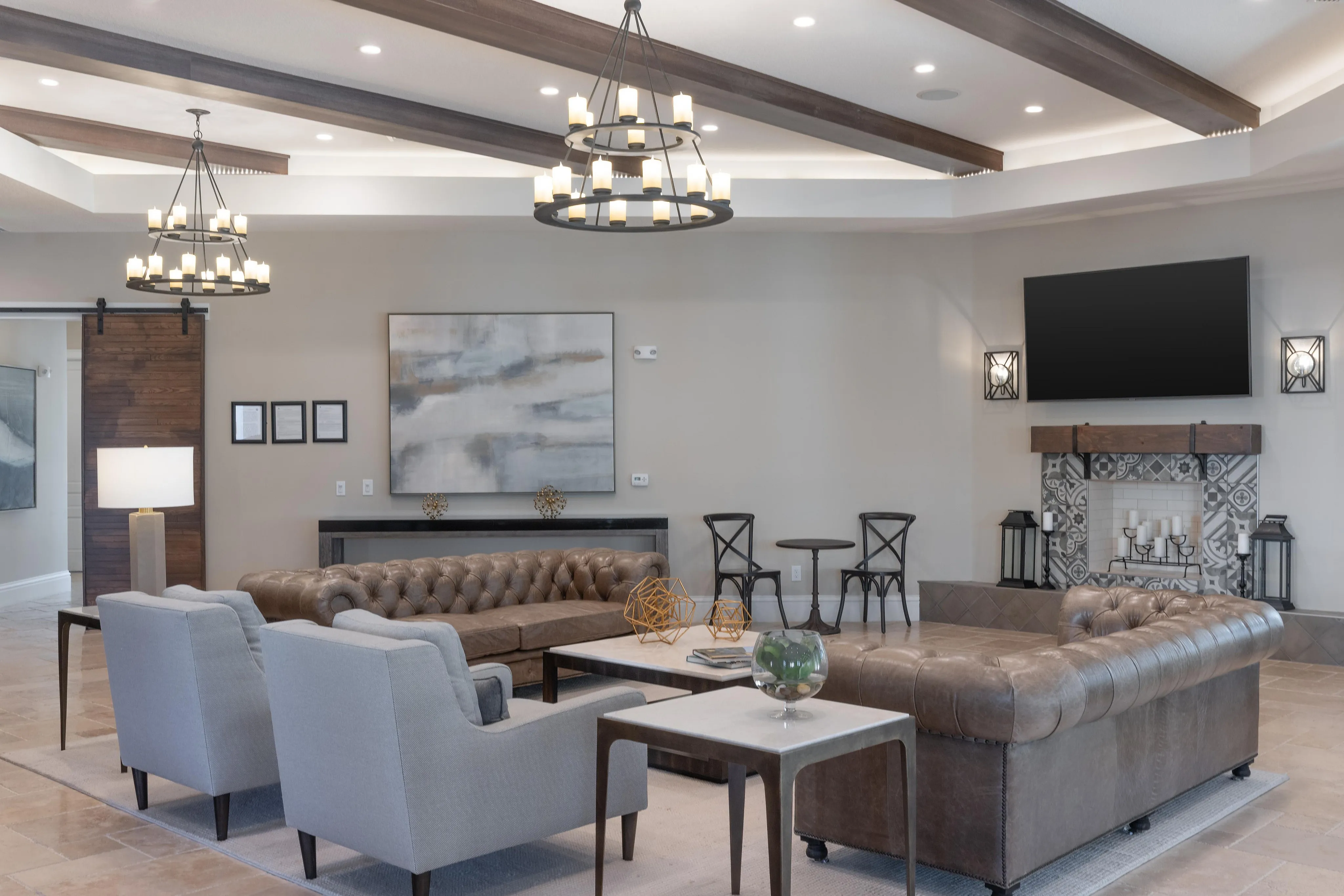 Luxurious living room with leather couches, stylish chandeliers, and a modern fireplace.