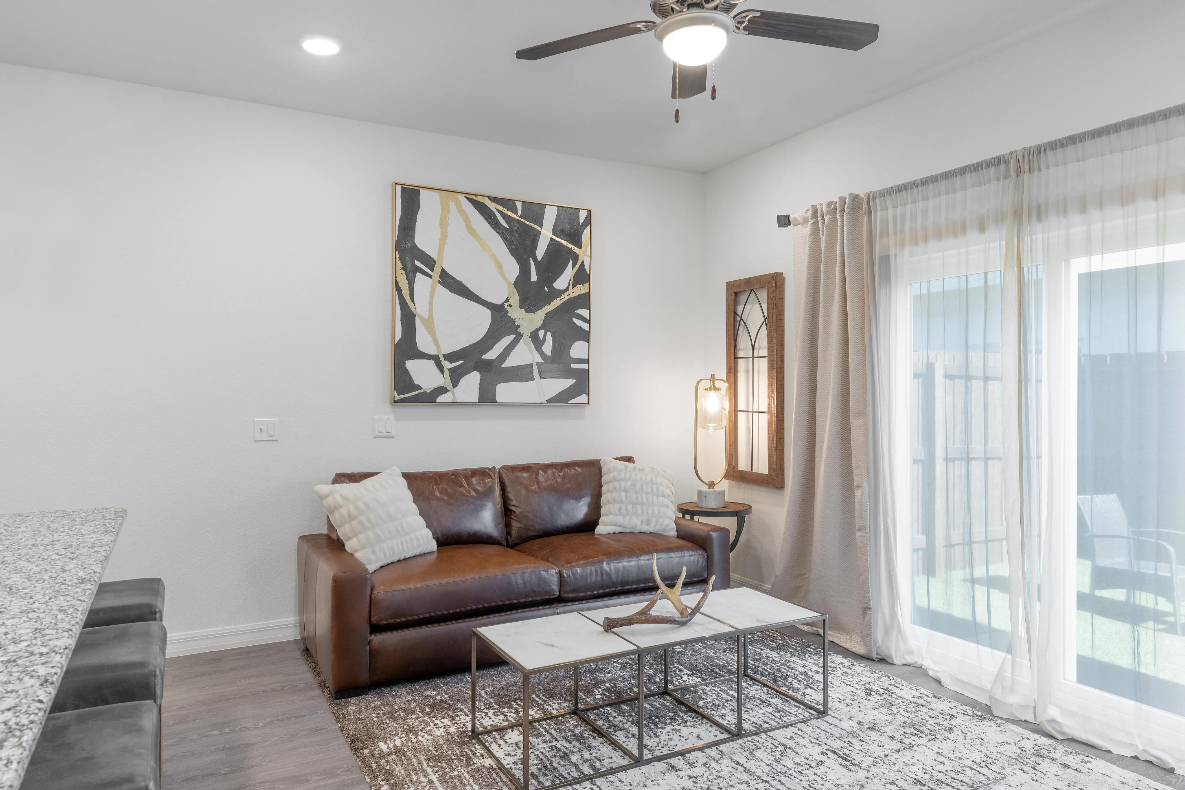 Bright and stylish living room featuring a leather sofa, abstract artwork, and a sleek coffee table.