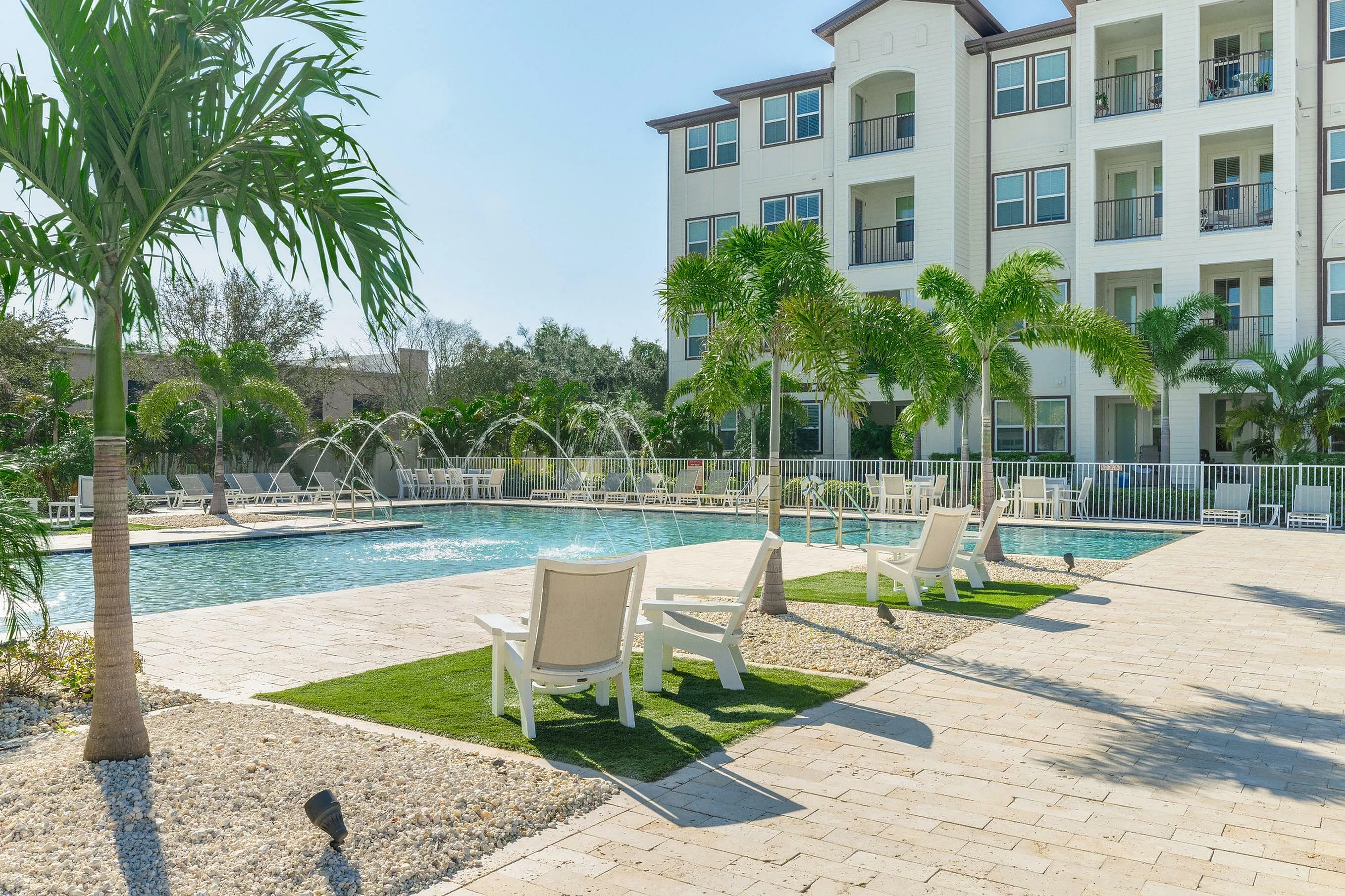 Luxurious apartment with a resort-style pool, surrounded by palm trees and sun loungers.