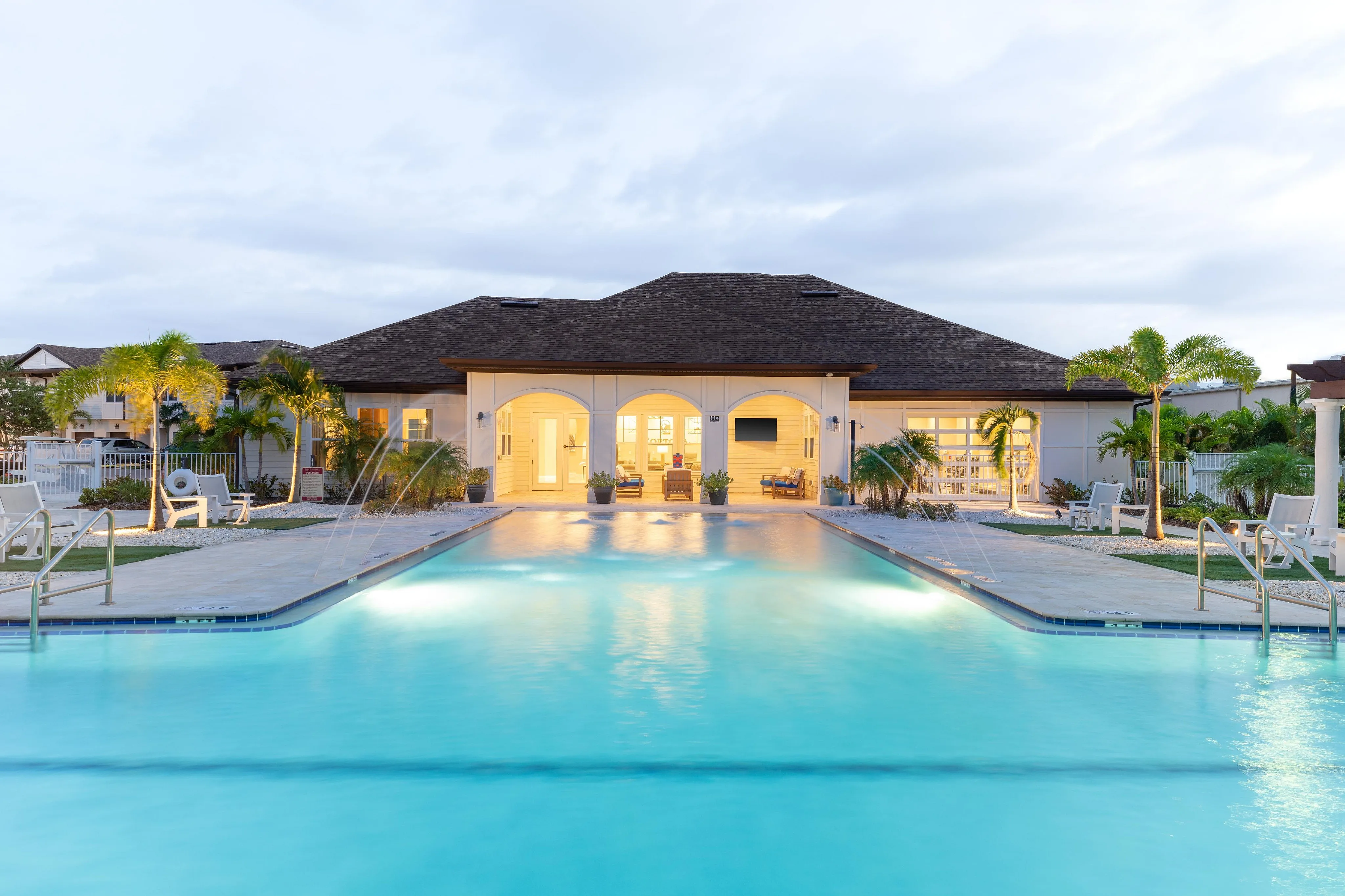 Elegant apartment complex with a stunning illuminated swimming pool and inviting outdoor lounge areas.