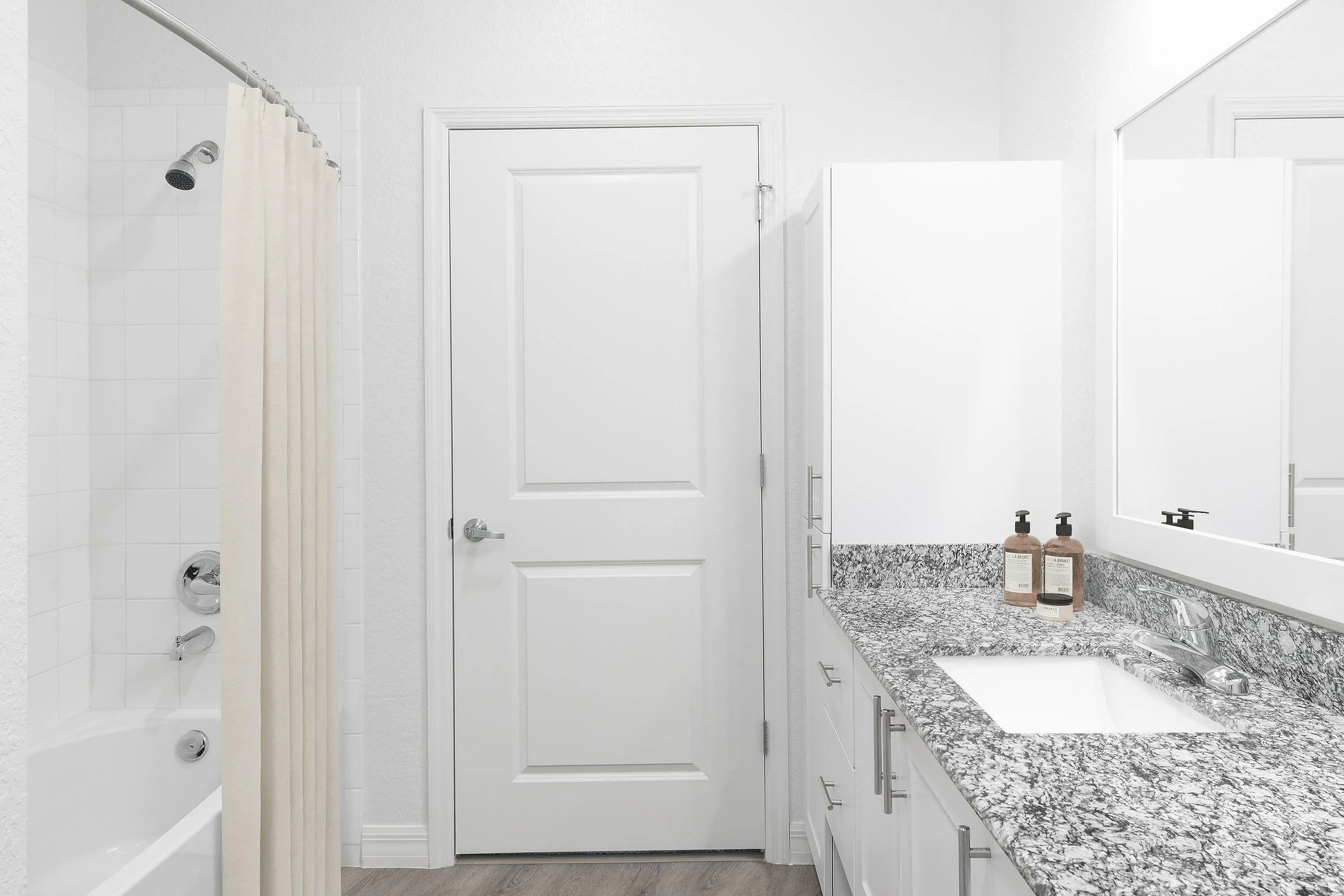 Bright and modern bathroom with granite countertop and white cabinetry.