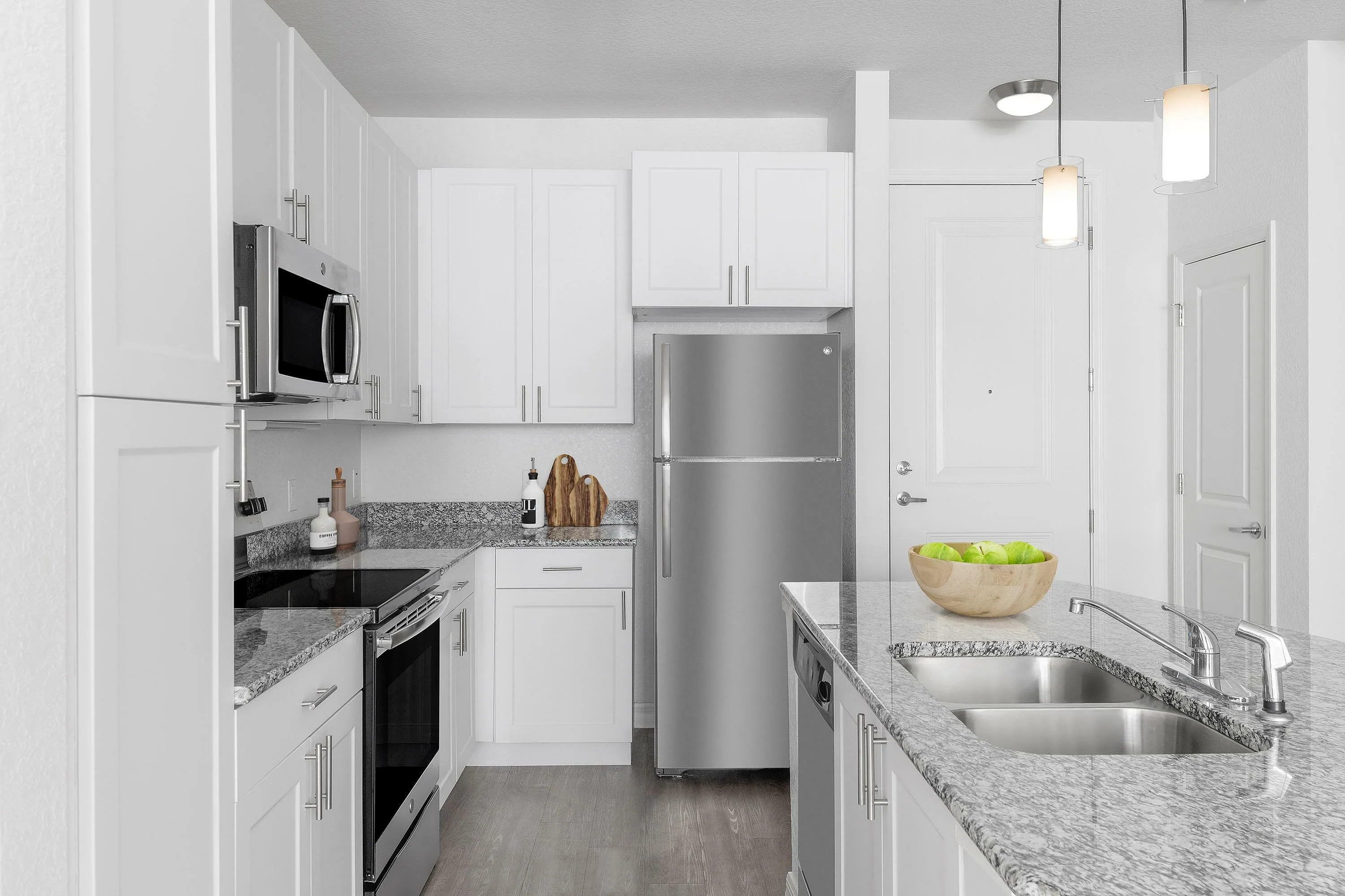 Contemporary kitchen with white cabinetry, stainless steel appliances, and granite countertops.