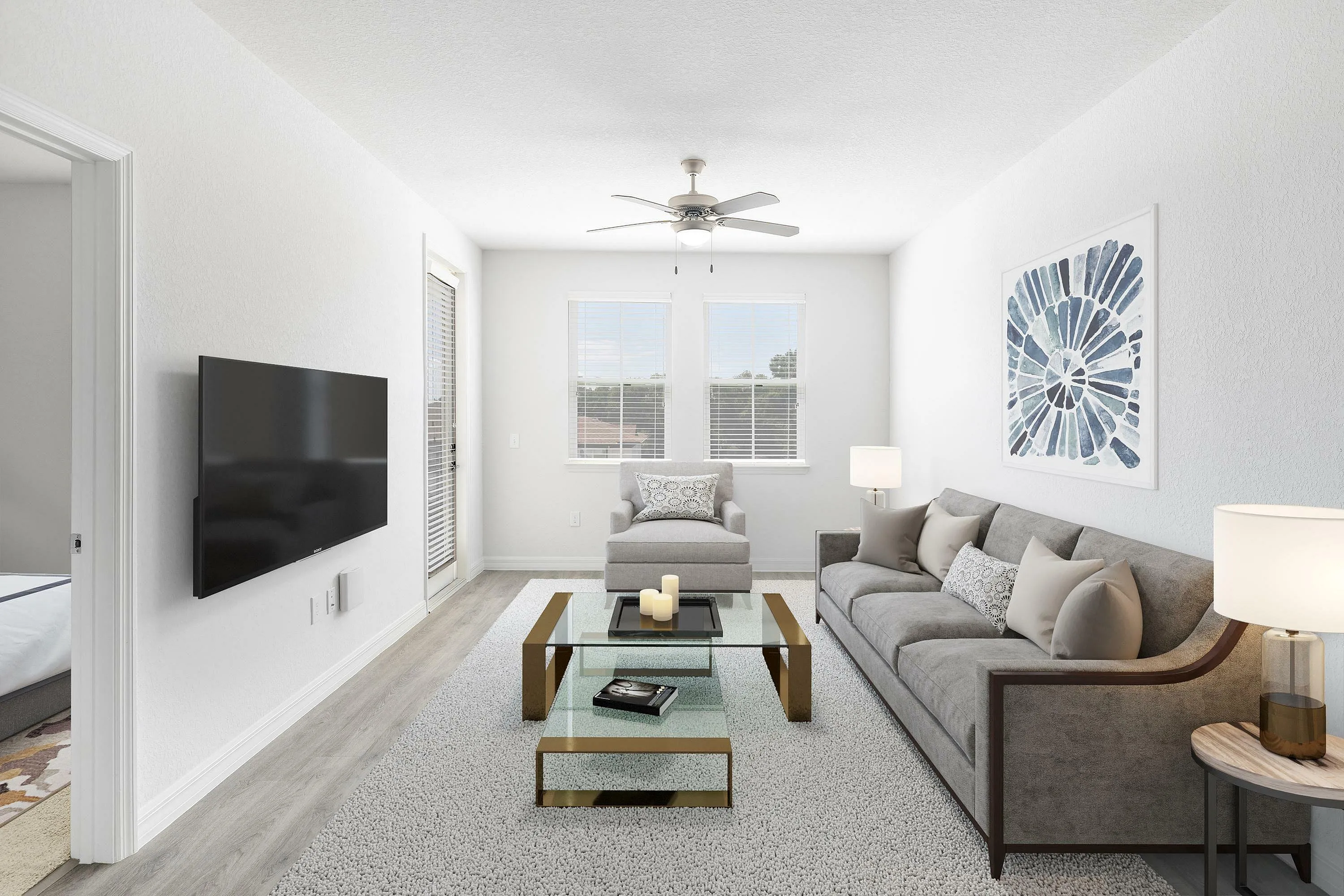 Bright and modern living room with a sleek sofa, glass coffee table, and wall-mounted TV.