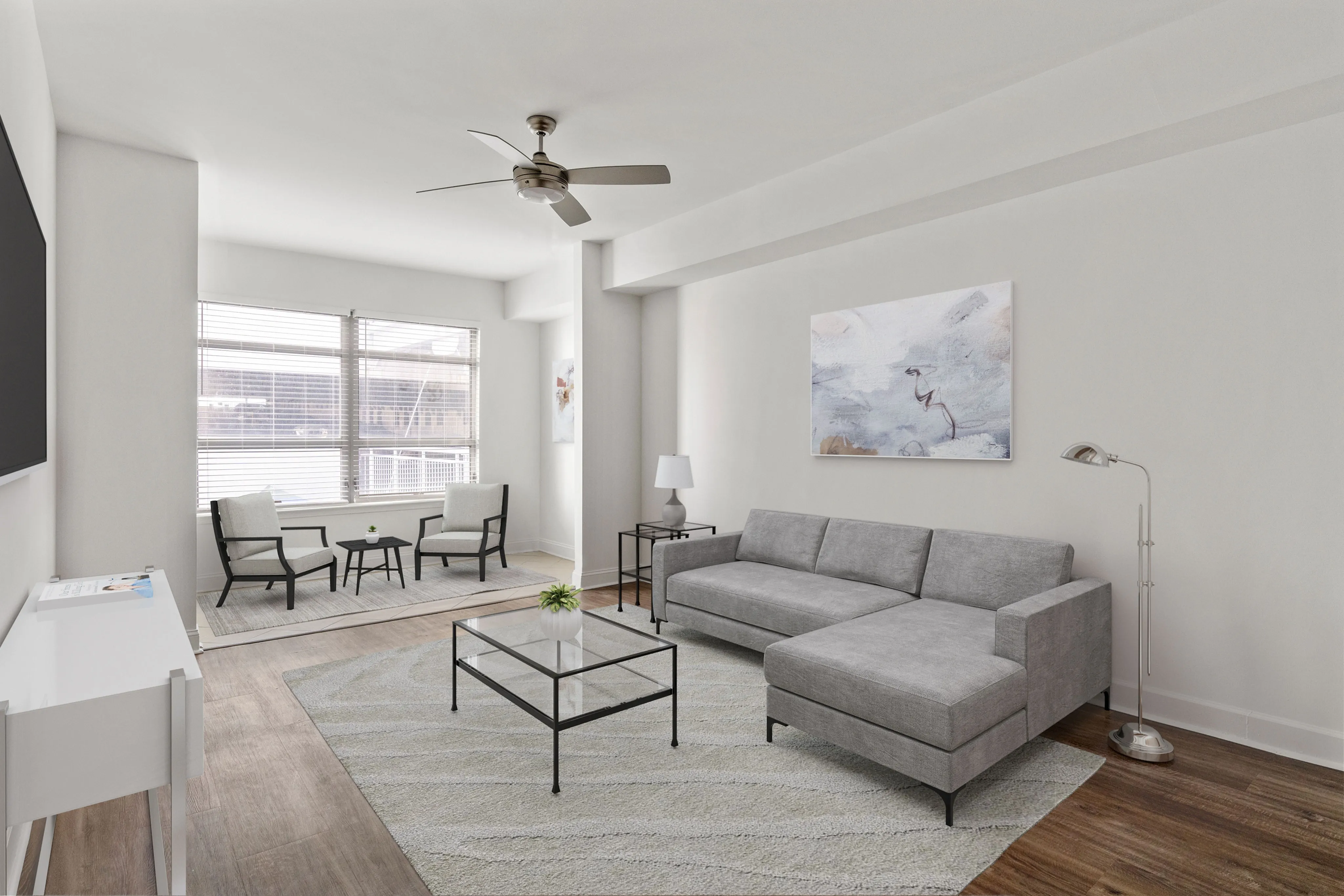 Furnished livingroom with grey sectional couch and nook with large window and sitting chairs