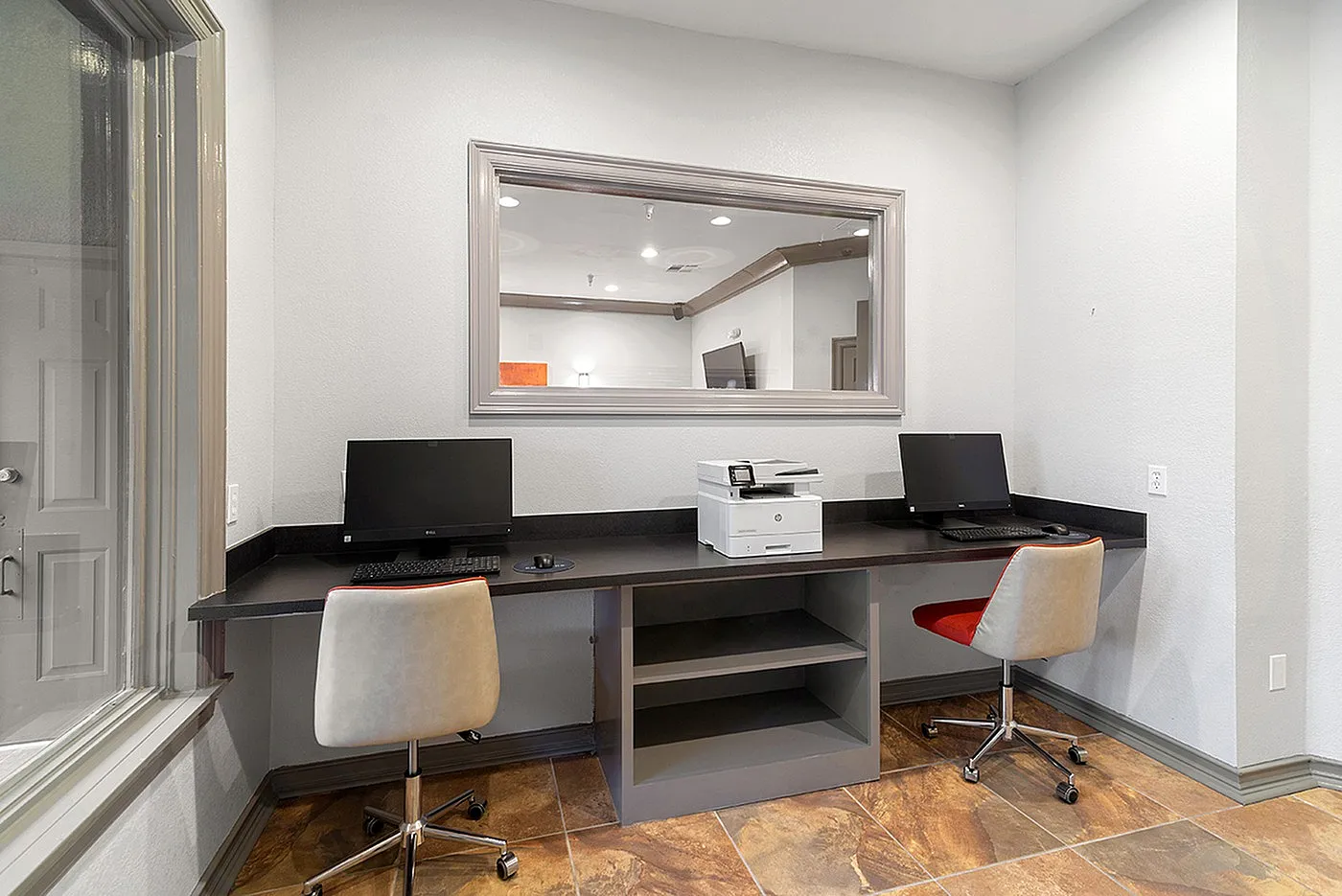 Modern workspace featuring dual computer stations with sleek design, comfortable chairs, and a convenient printer on a stylish countertop.