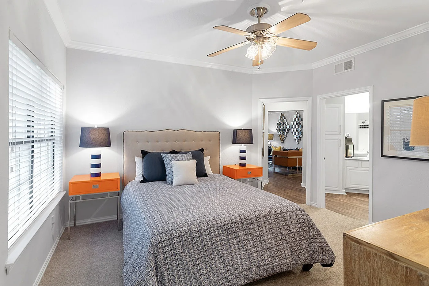 Inviting bedroom with elegant decor, featuring a plush bed, stylish side tables with chic lamps, and a view into a cozy living area.