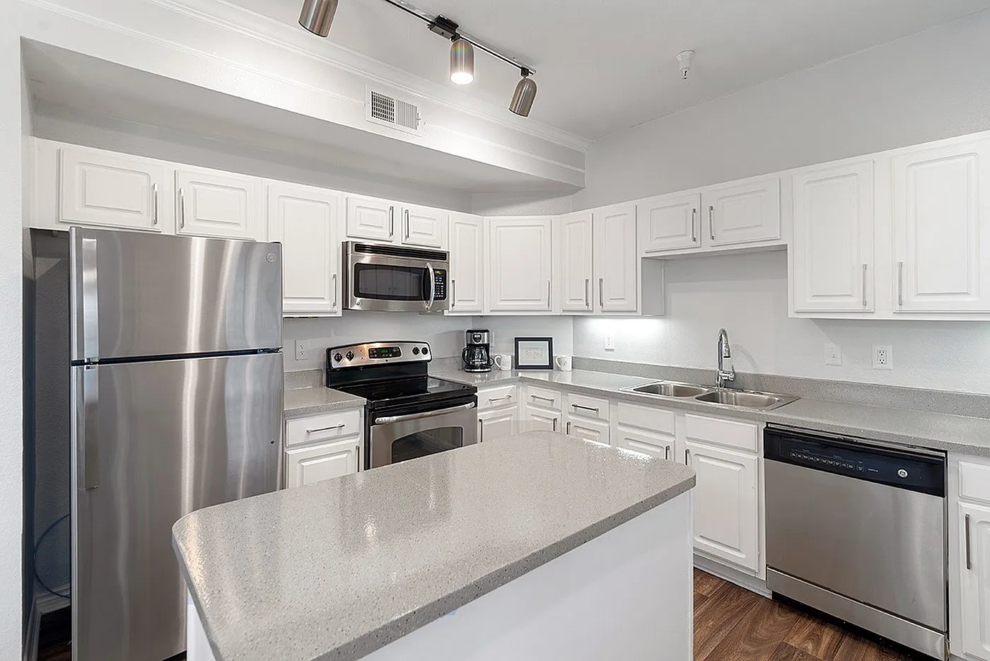 Modern kitchen with sleek stainless steel appliances, pristine white cabinetry, and elegant countertops.