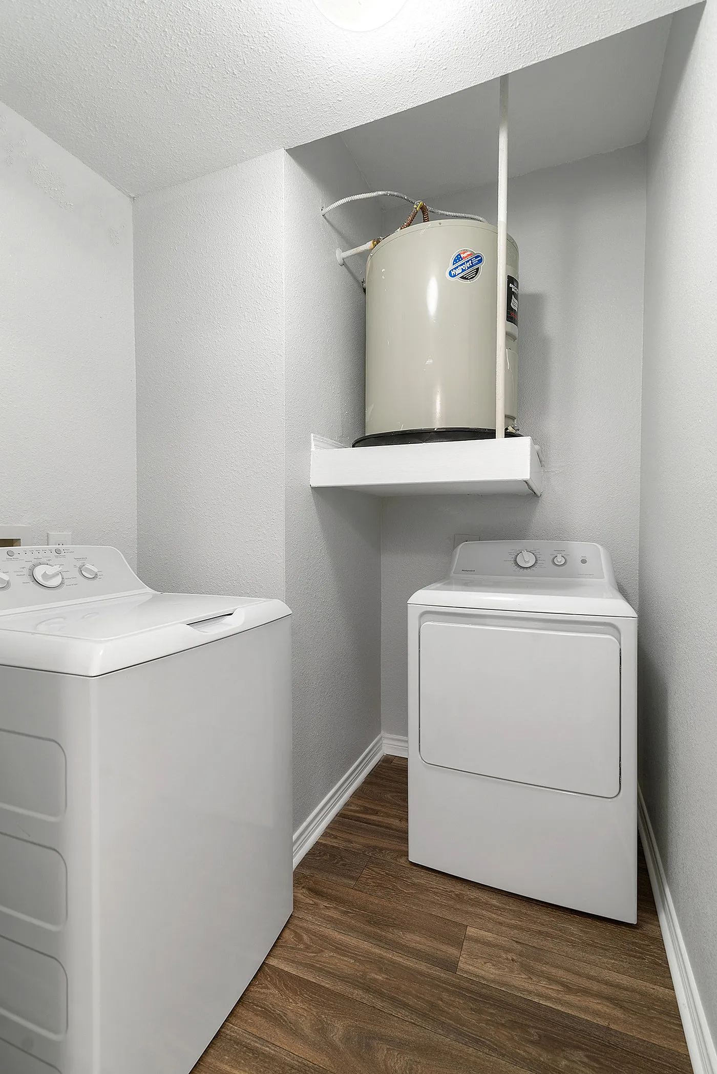 Modern laundry room with sleek washer and dryer, accented by stylish wood flooring and bright white walls.
