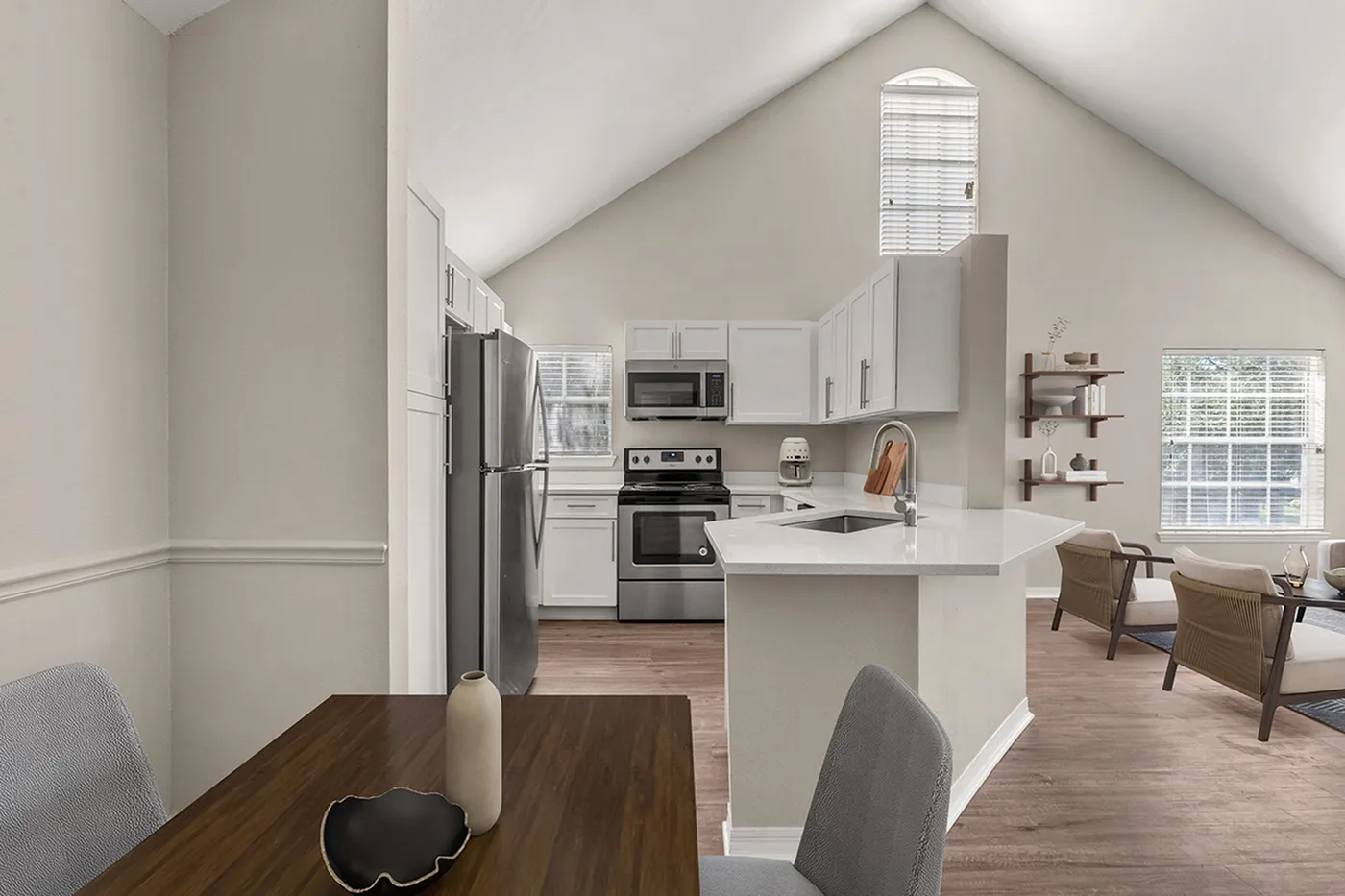 Modern open-concept kitchen and dining area with sleek stainless steel appliances, elegant white cabinetry, and a cozy living space featuring natural light.