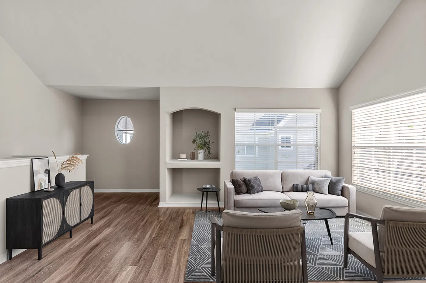 Elegant living room with modern decor, featuring a plush sofa, stylish armchairs, and abundant natural light from large windows.