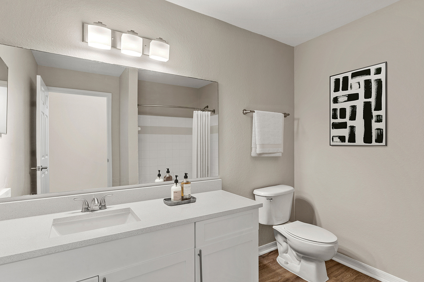 Modern bathroom with sleek white vanity, elegant light fixtures, and contemporary wall art.