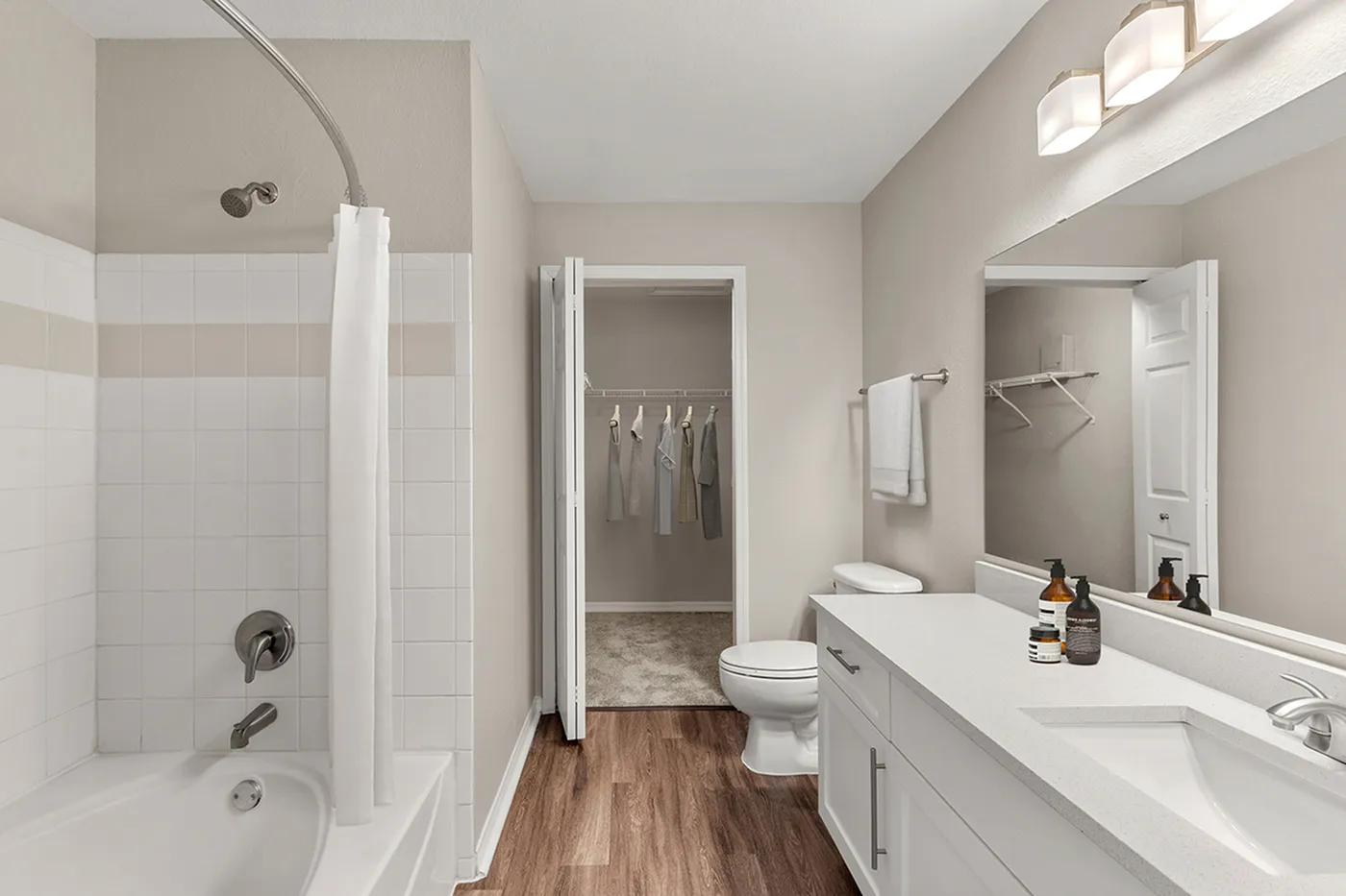 Modern bathroom with elegant white cabinetry, chic countertop, and a relaxing bathtub adjacent to a spacious walk-in closet.