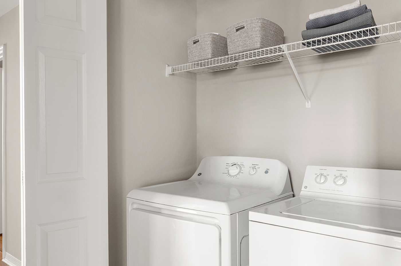 Contemporary laundry room with modern washer and dryer, ample shelving for storage, and neutral decor.