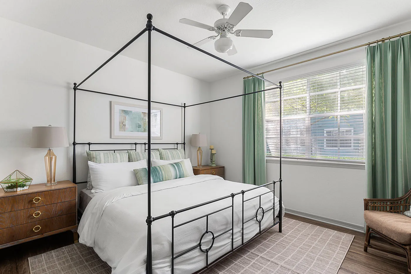 Elegant bedroom with a canopy bed, modern decor, and a large window framed by green curtains, creating a serene ambiance.
