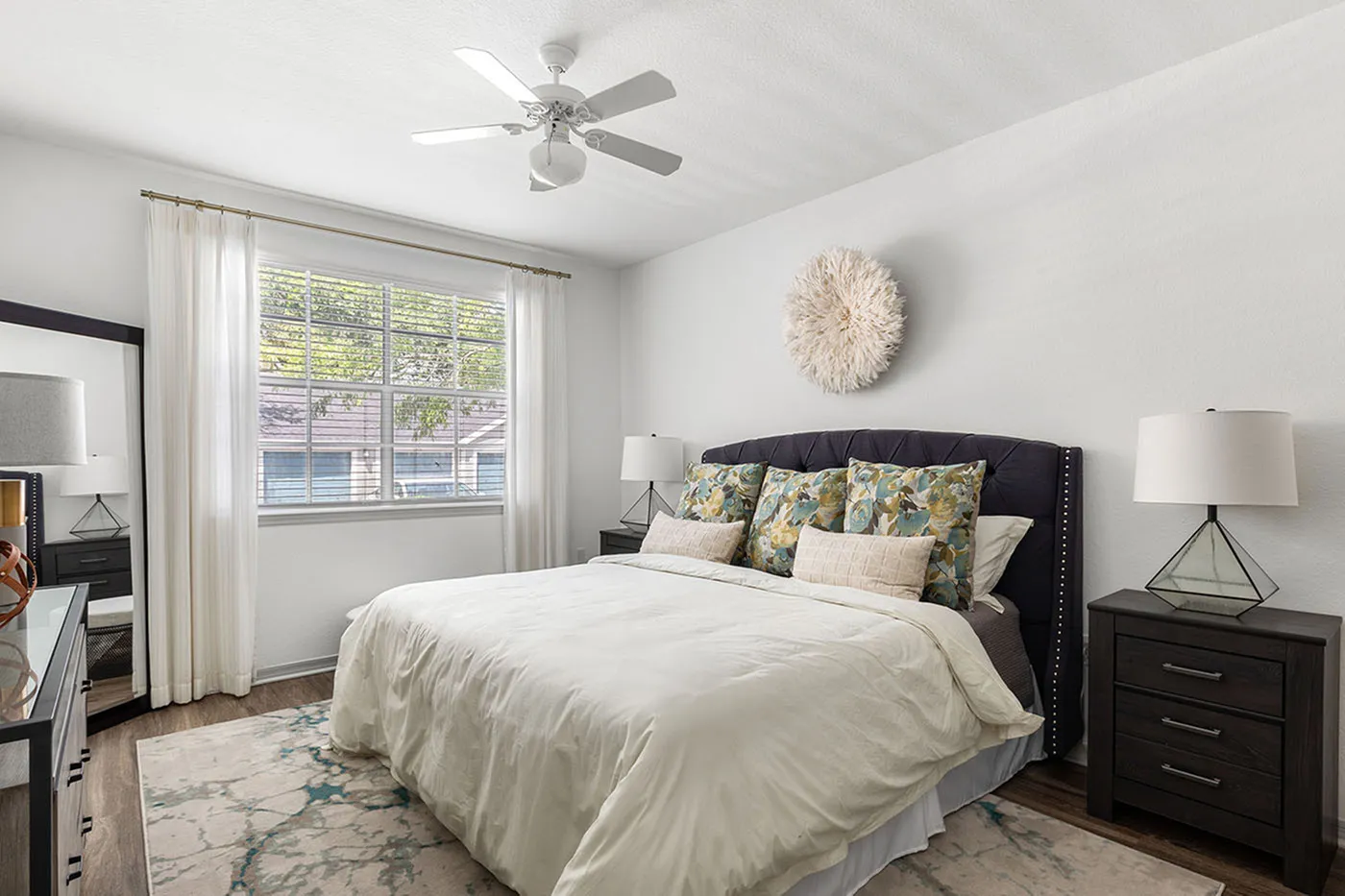 Bright, inviting bedroom with a plush bed, elegant decor, and abundant natural light through a large window.