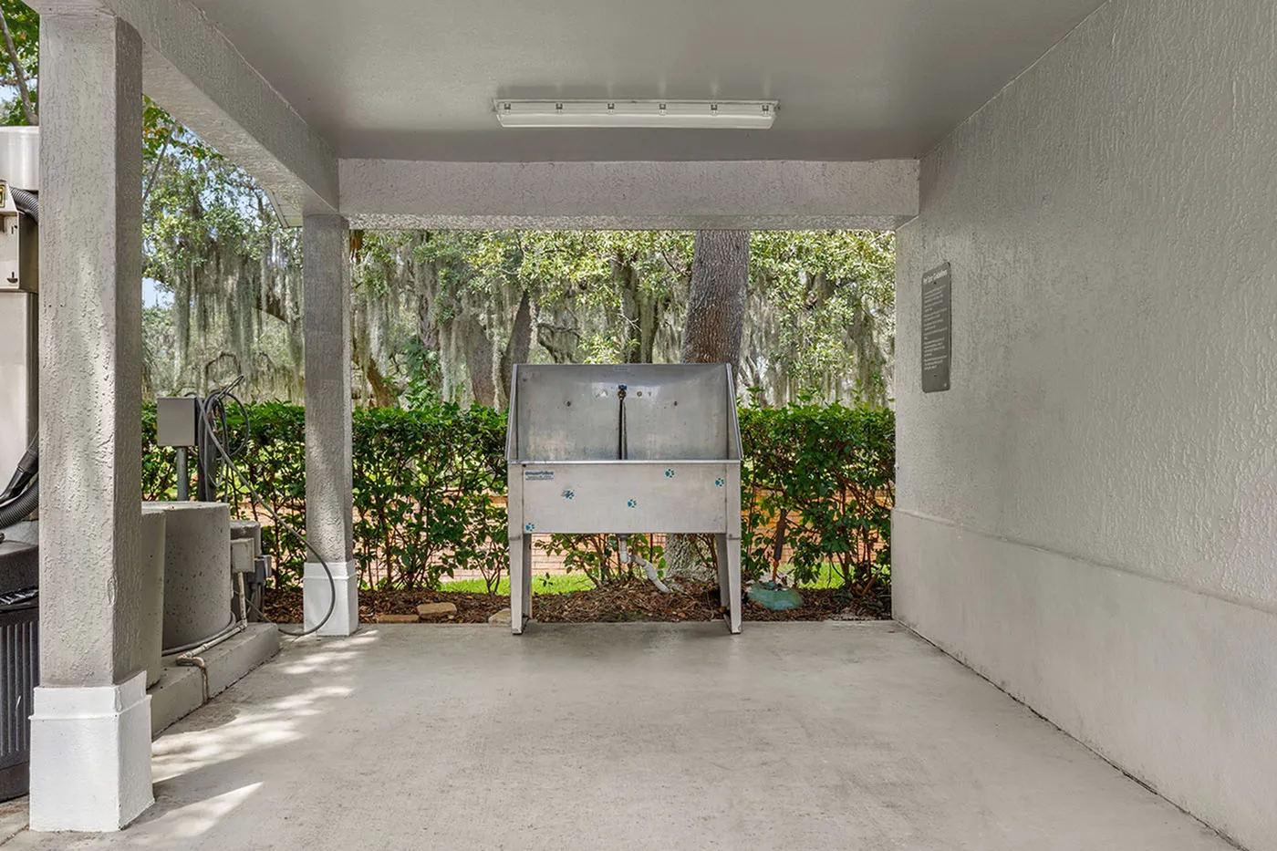 Covered outdoor area featuring a stainless steel wash station surrounded by lush greenery, offering a serene and functional space.