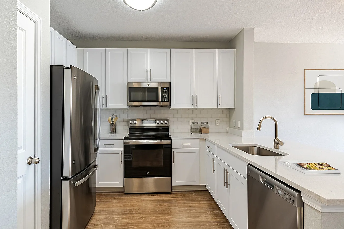 Modern kitchen with sleek stainless steel appliances, white cabinetry, and elegant countertops, perfect for culinary enthusiasts.