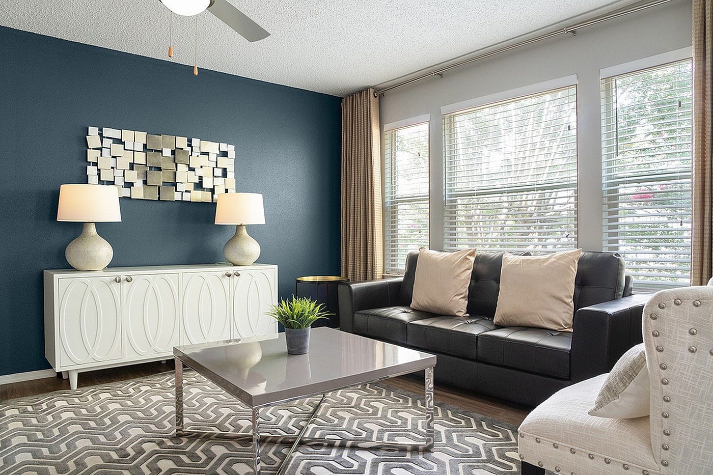 Bright and inviting living room featuring modern decor, a sleek black sofa, and elegant lighting against a rich accent wall.