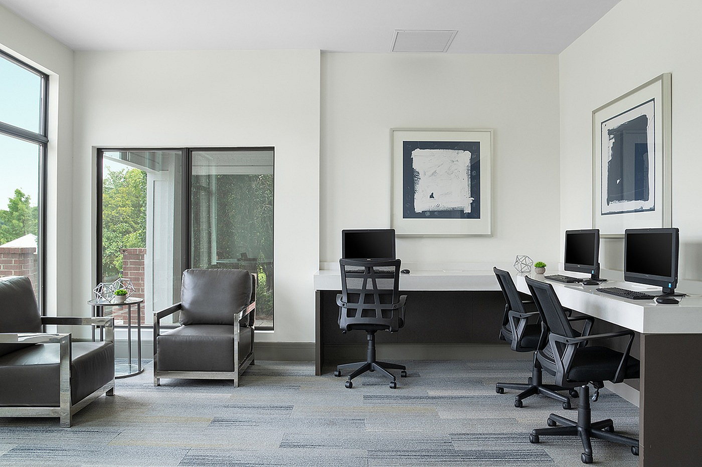 Updated business center with sleek computers, elegant leather chairs, and large windows for natural light.