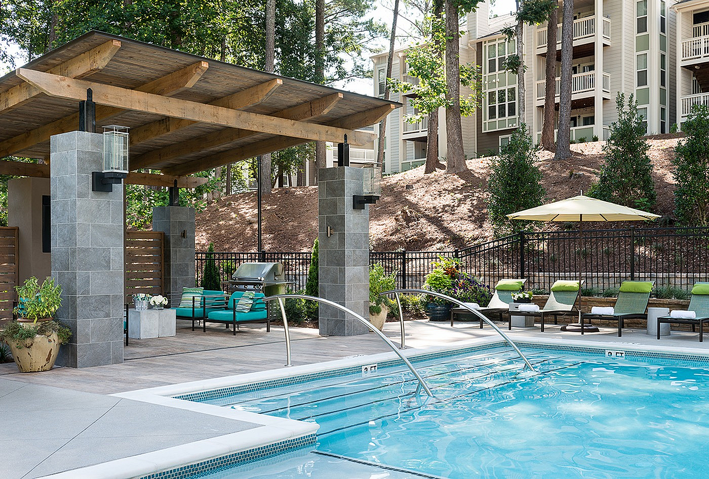 Luxurious poolside oasis with comfortable lounge chairs, shaded seating area, and lush greenery, perfect for relaxation and entertainment.