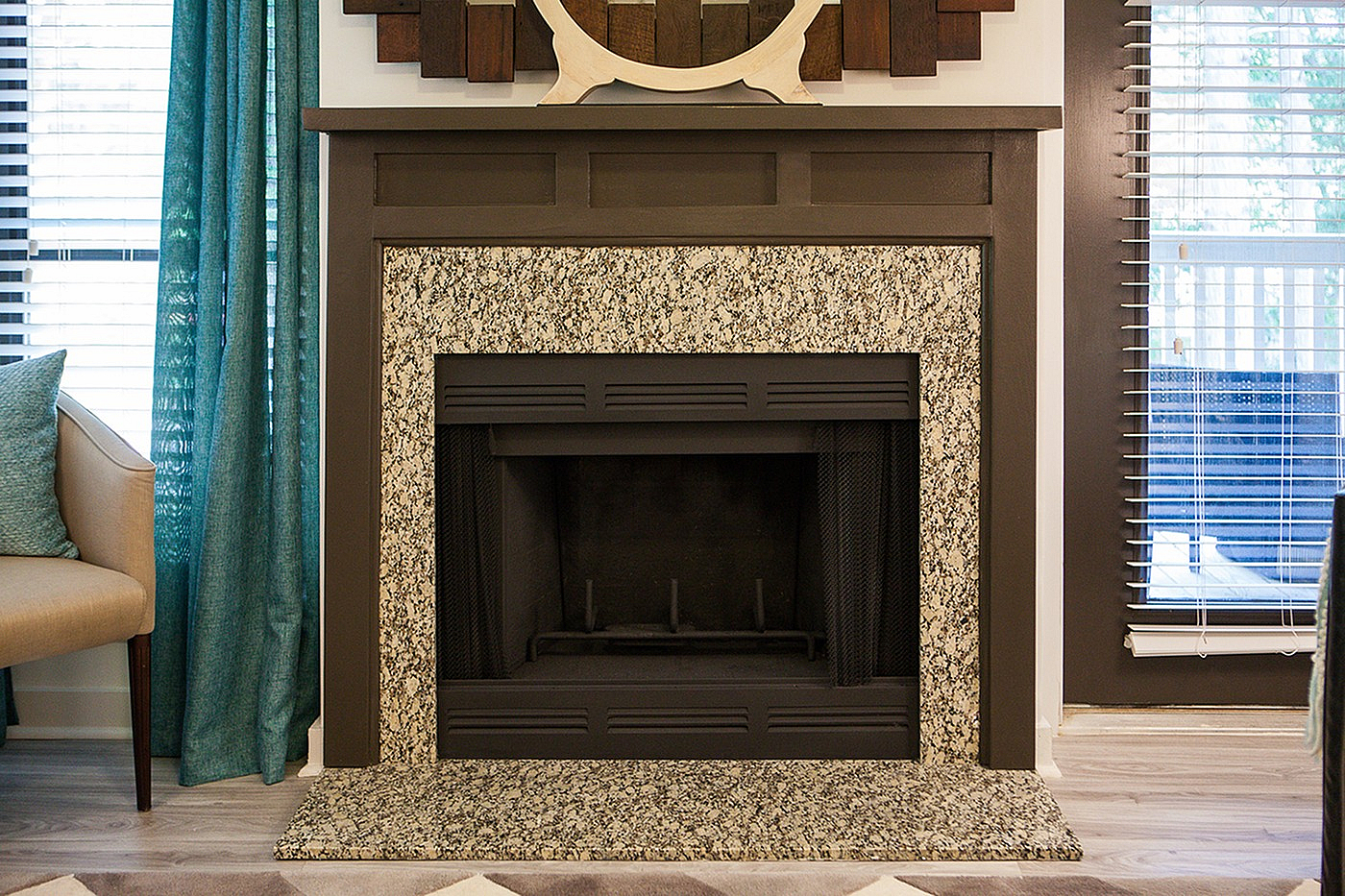 Charming living space with a beautifully designed granite fireplace, surrounded by elegant decor and serene teal curtains.