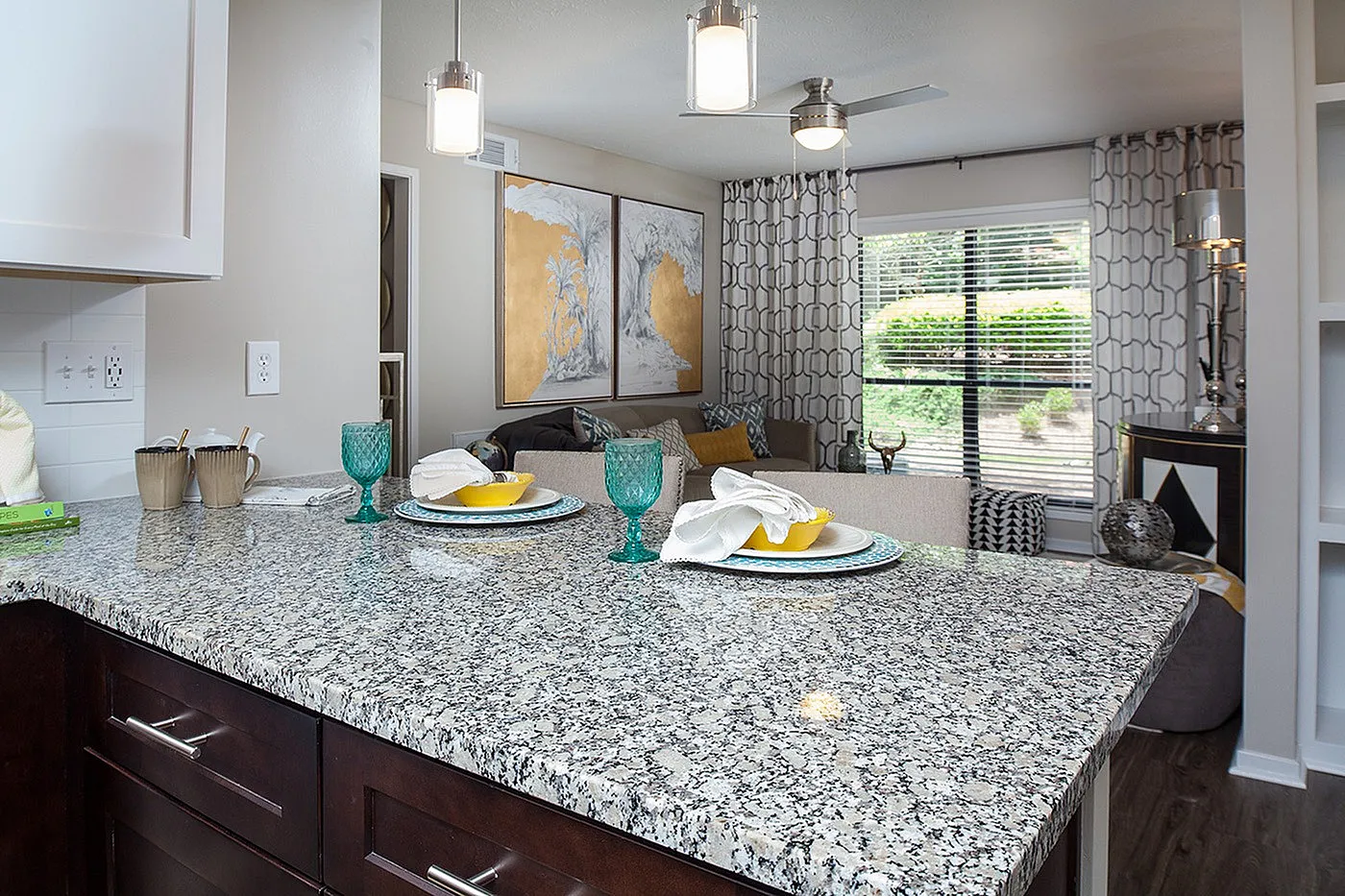 Contemporary apartment with elegant granite countertop, stylish dining setup, and cozy living area featuring chic decor and large windows offering garden views.