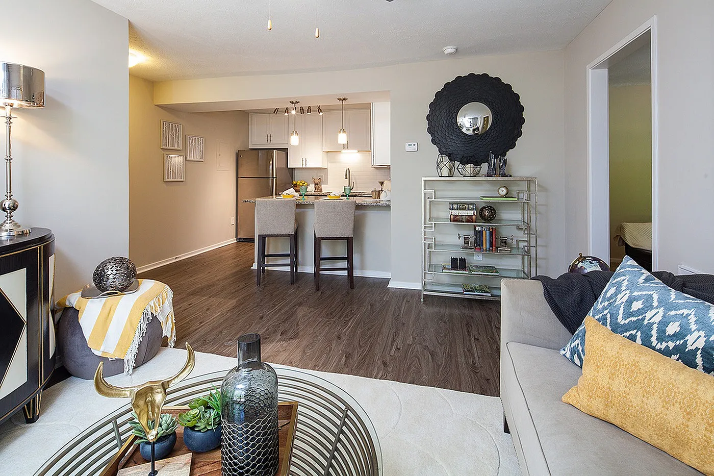 Inviting open-plan living area featuring a cozy couch, elegant decor, modern kitchen with stainless steel appliances, and stylish bar seating.