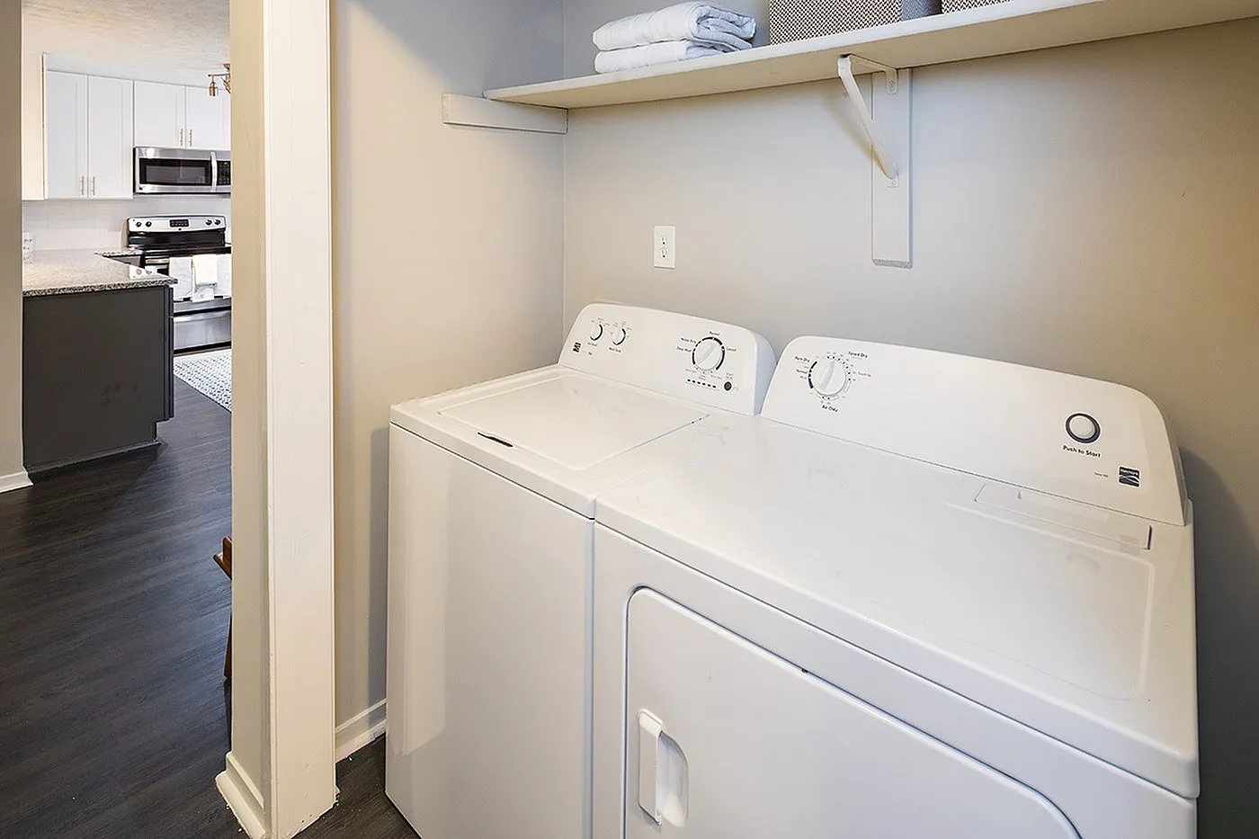 Chic apartment laundry area featuring modern washer and dryer with adjacent stylish kitchen visible.