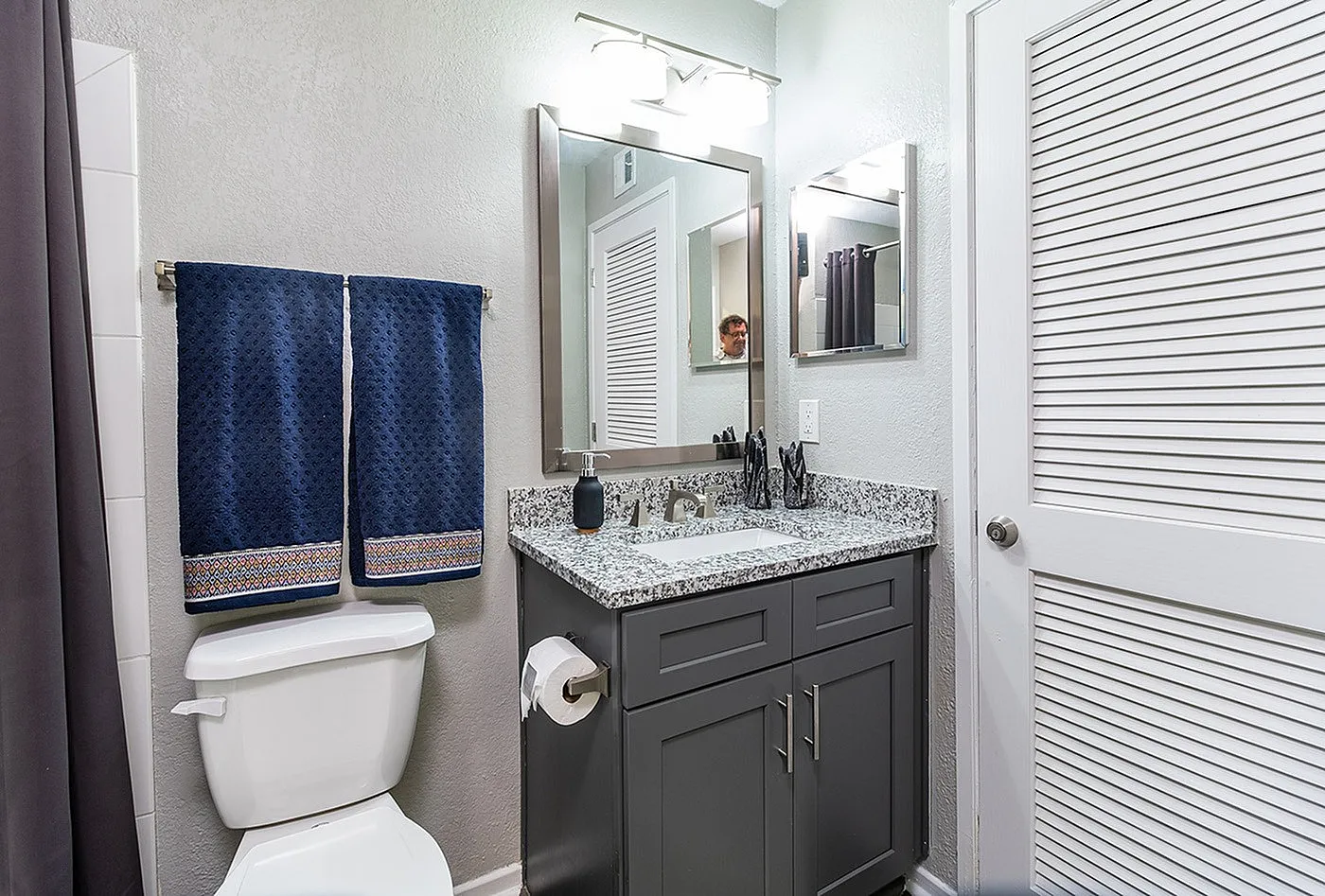Chic bathroom with elegant granite countertop, modern fixtures, and plush navy towels, creating a serene oasis.