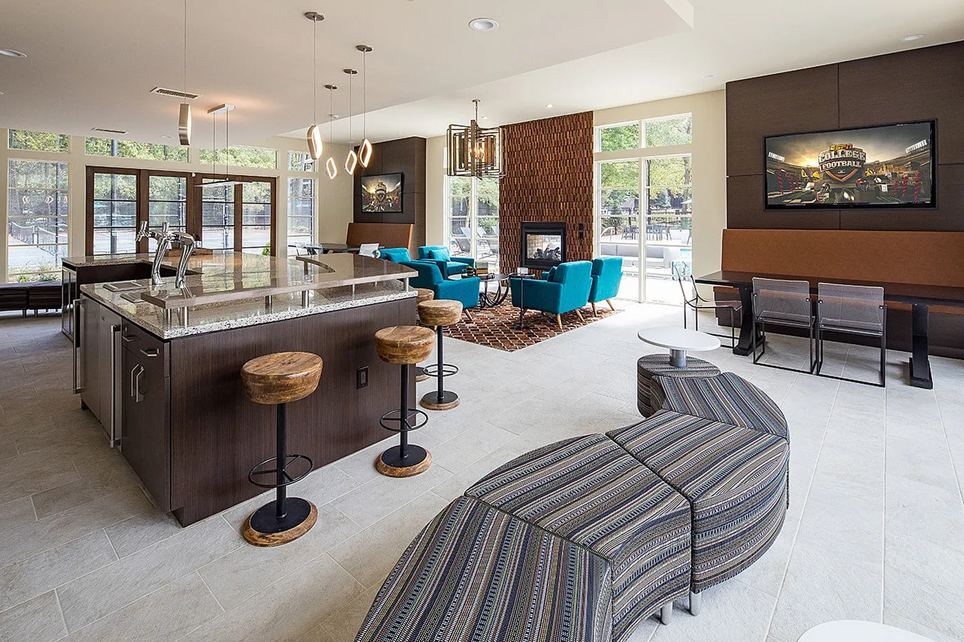Chic open-concept lounge featuring modern kitchen, vibrant teal seating, and large windows for natural light.