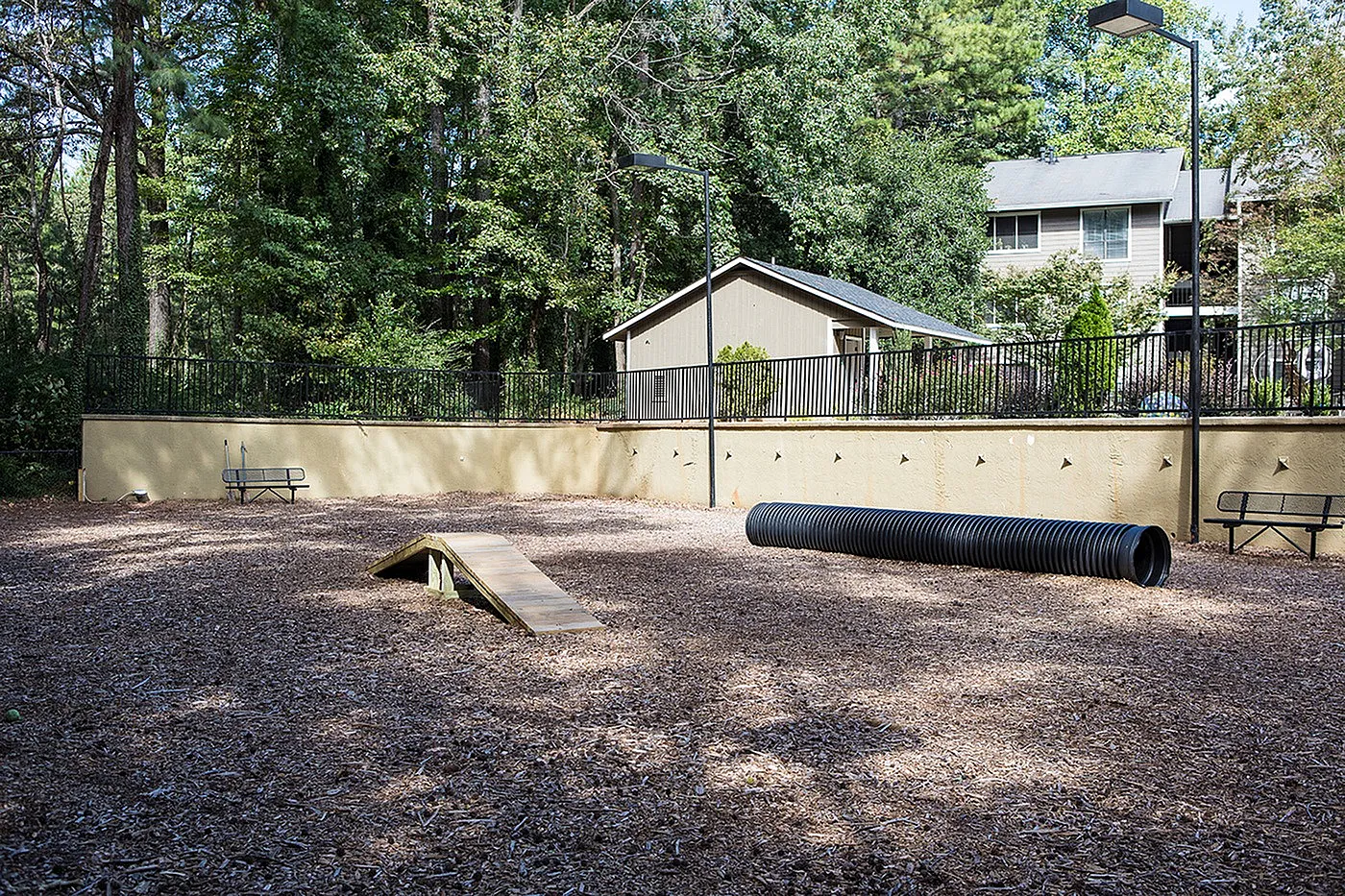 Inviting outdoor dog park with agility equipment set amidst lush greenery, perfect for pet-friendly living.
